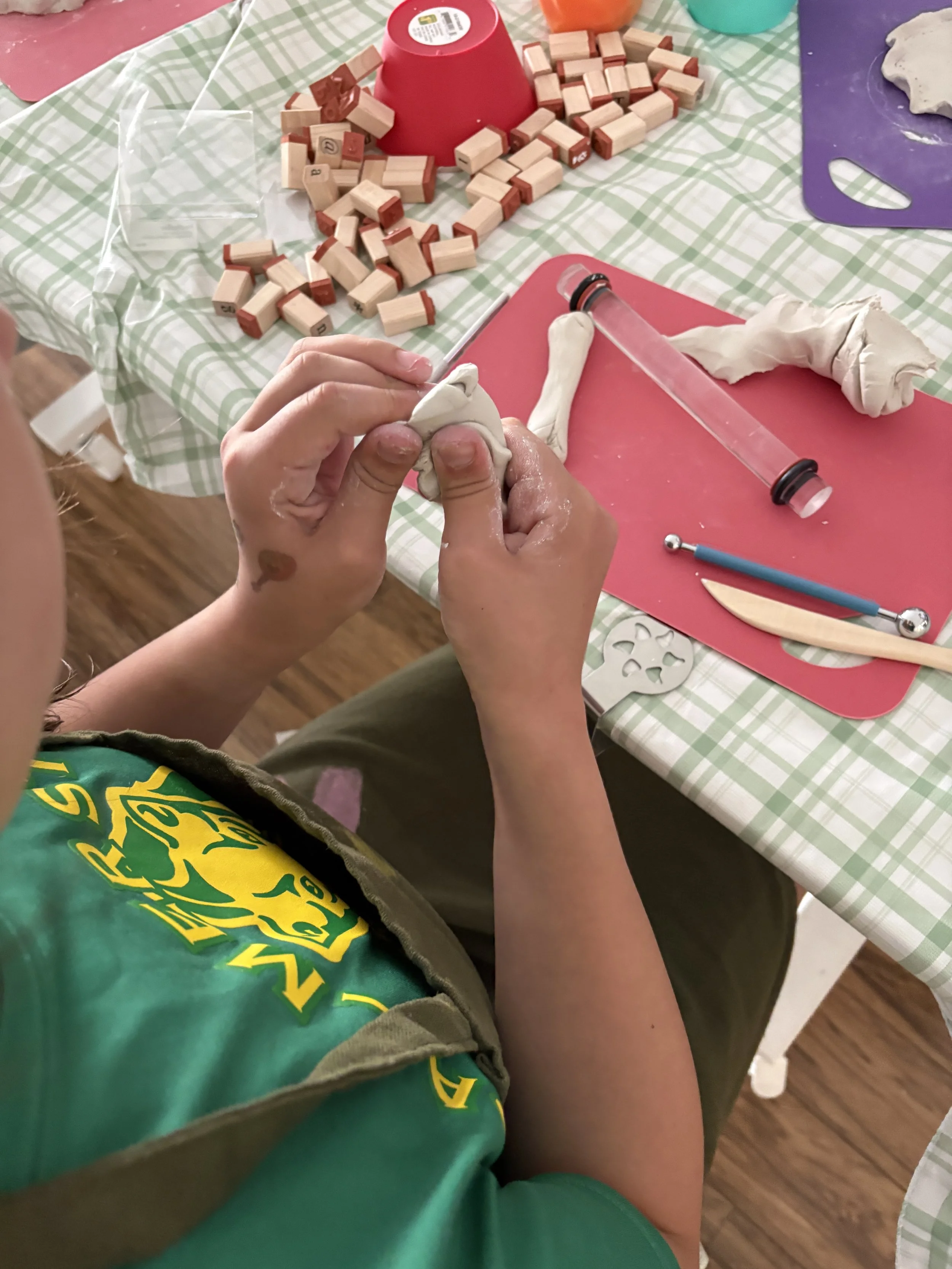 A kid in a green shirt shaping clay with her hands