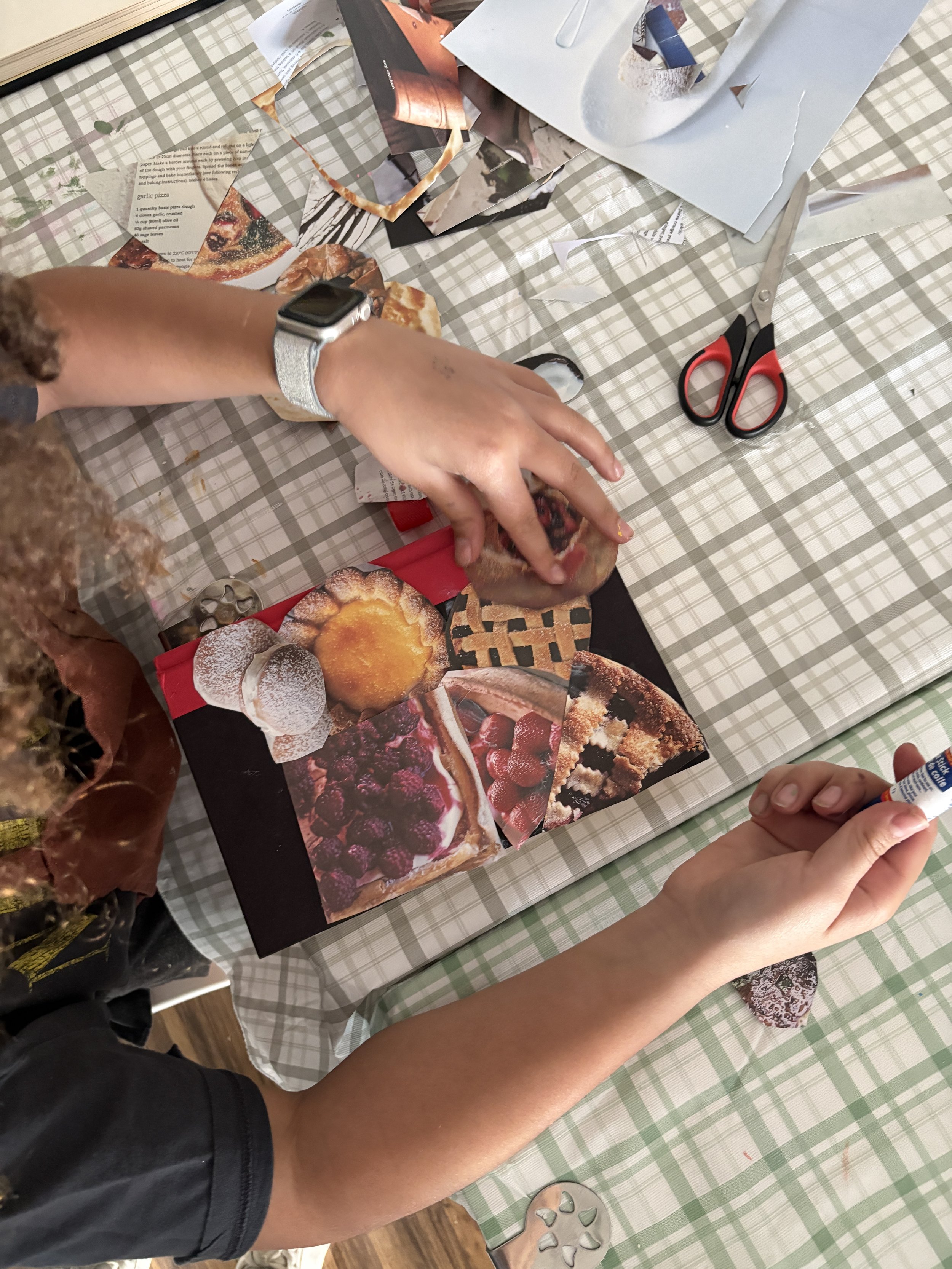 A kid pasting pictures of food to make a collage on the front of a book
