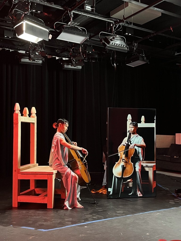 Cellist performing in John Aylward’s Moondial, shown with his reflection to evoke the work’s themes of duality, shifting identity, and mirrored musical time.
