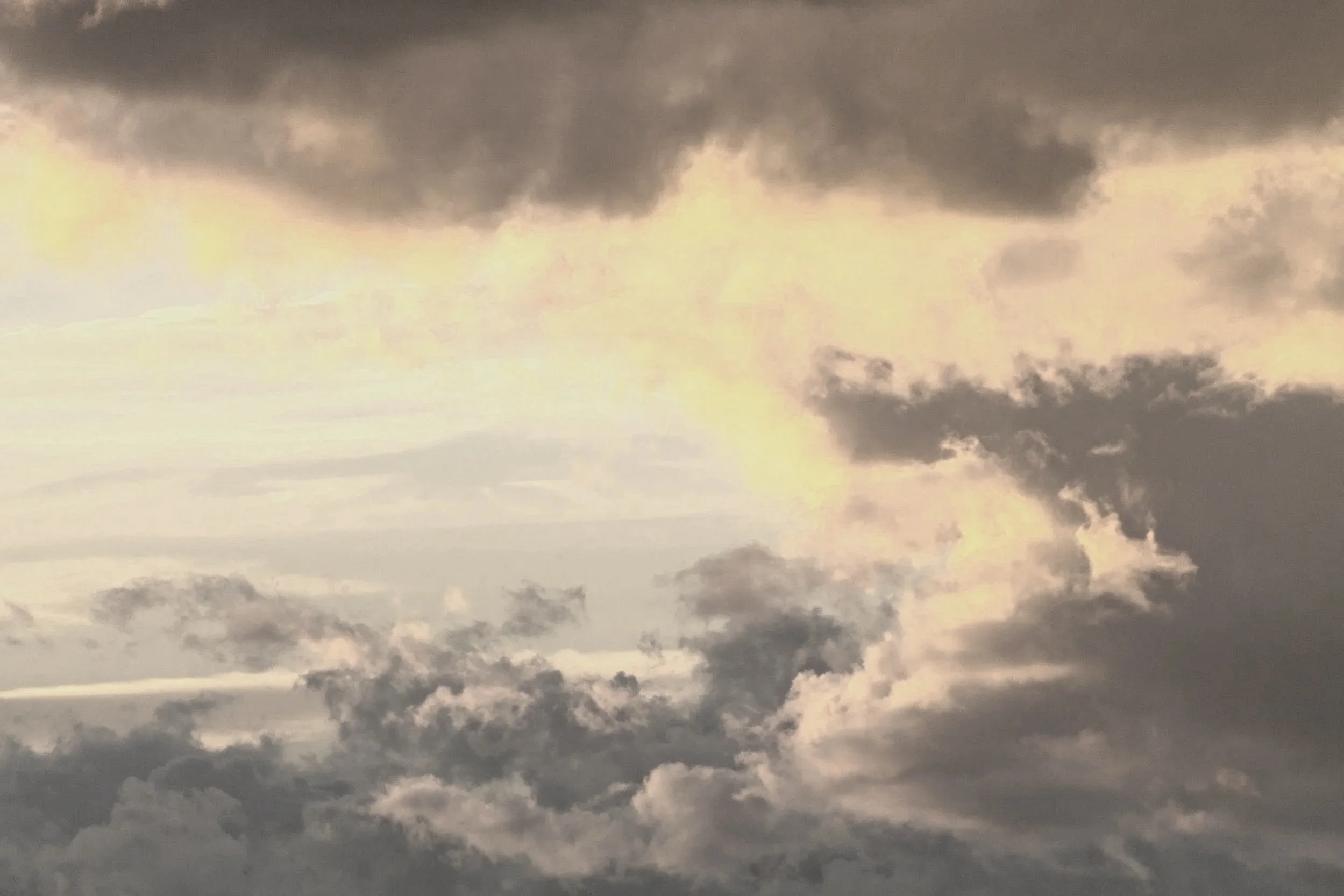 Dark storm clouds in the sky with a hint of sunlight breaking through reflecting the dynamic soundscapes of John Aylward.