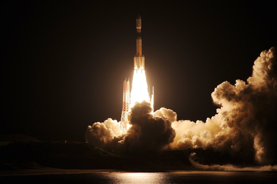 A NASA rocket launching at night with bright flames and smoke.