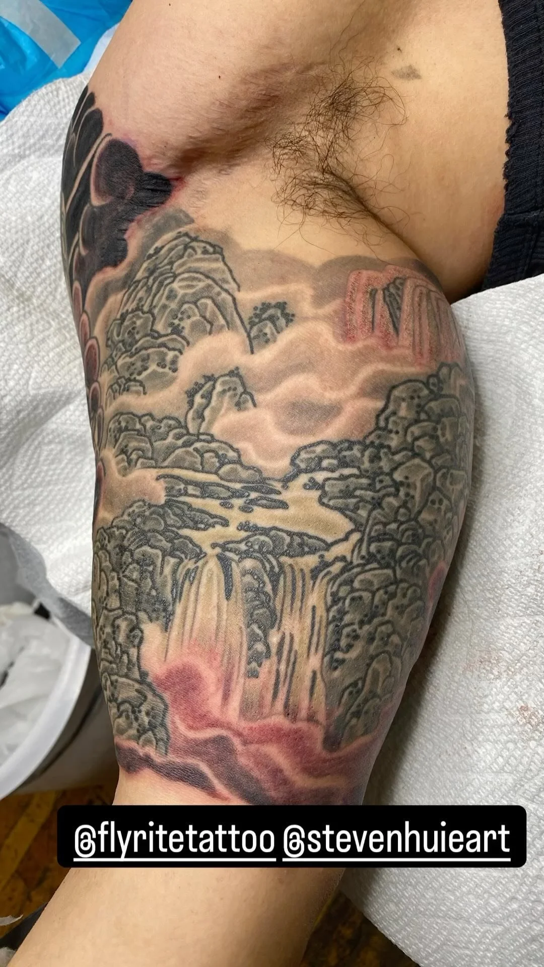 Tattoo of a mountainous landscape with waterfalls on a person's thigh.