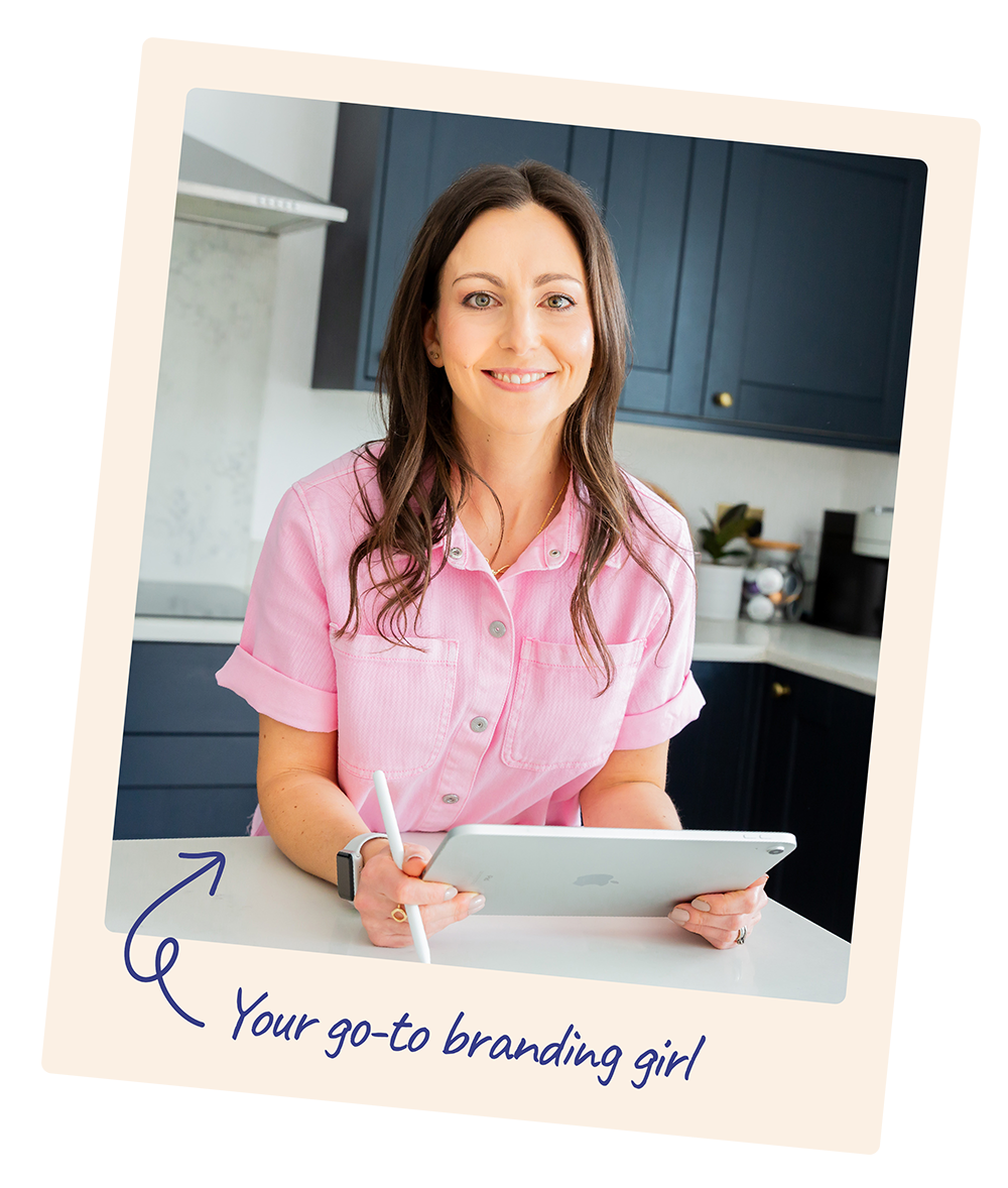 A woman smiling while holding an iPad and a stylus in a modern kitchen. She is wearing a pink shirt and has long, dark hair., graphic designer at Lauren Design Studio
