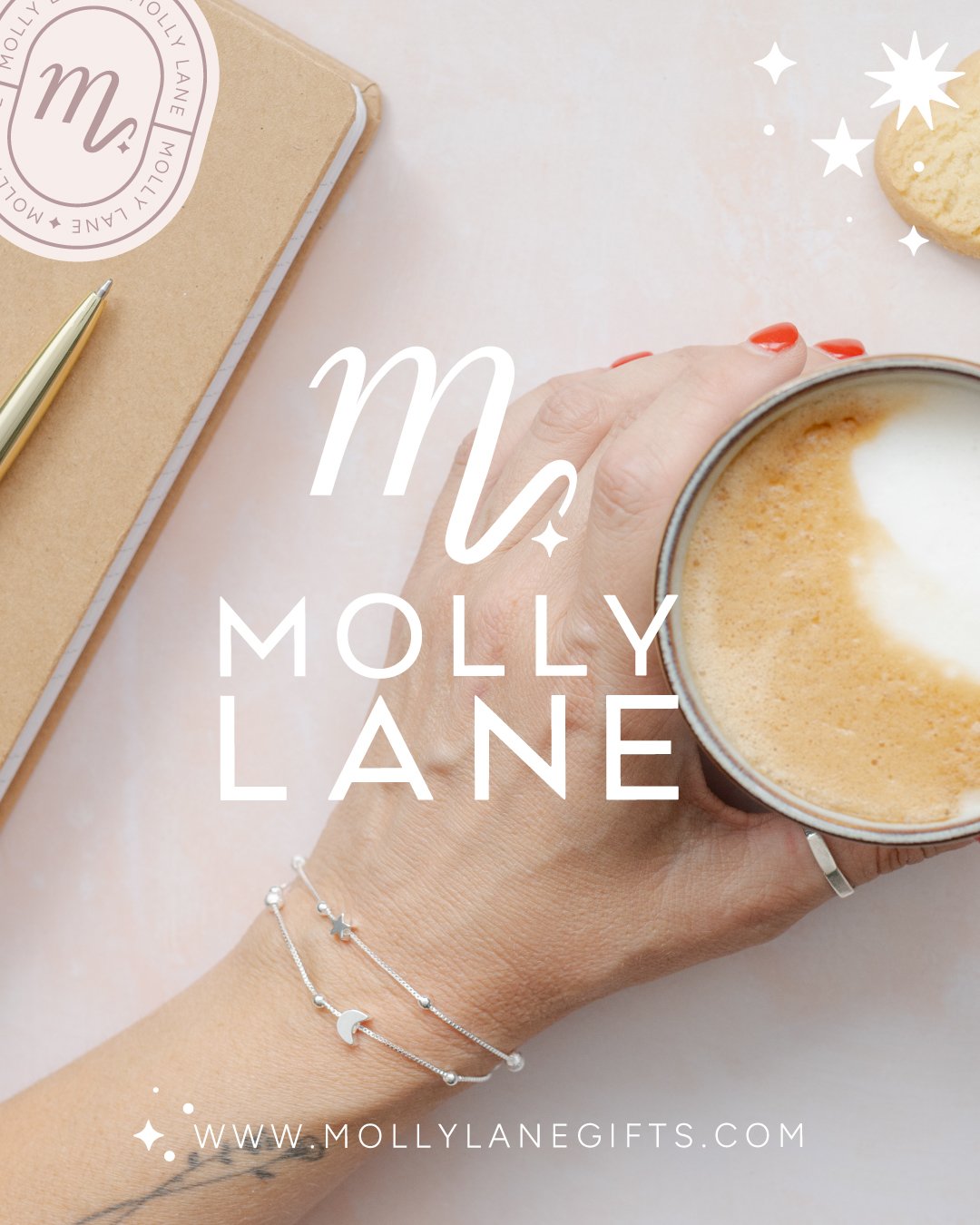 A hand holding a coffee cup with foam art, a notebook with an Emily Lane sticker, a gold pen, and a decorated bracelet on the wrist. There are also star and sparkle graphics and a cookie on the white surface.