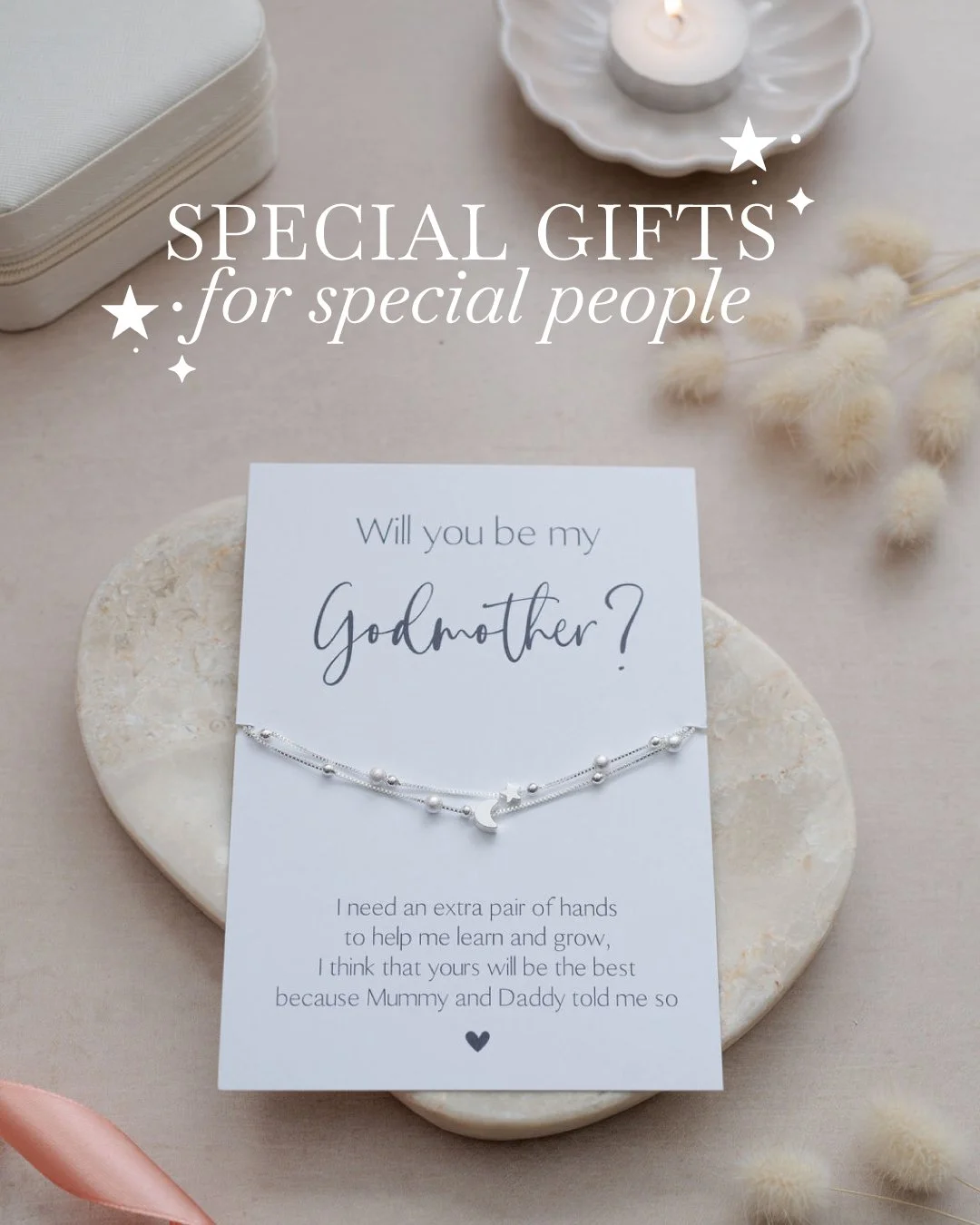 A birthday or special occasion card asking 'Will you be my Godmother?' with a delicate bracelet and decorative items in the background.