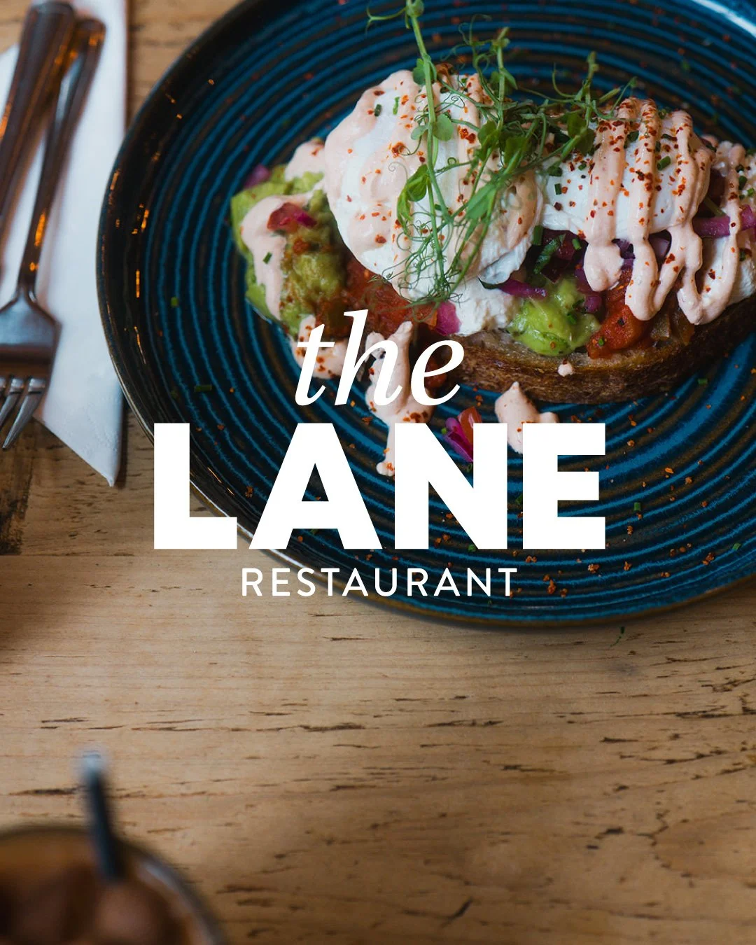 A close-up of a plated dish with avocado, sour cream, and microgreens on toast at The Lane Restaurant.