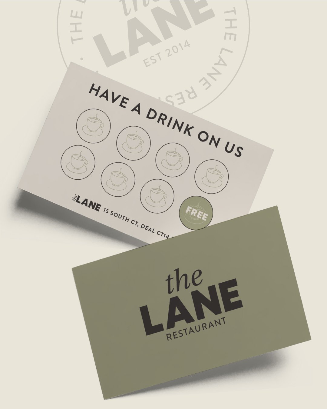 A promotional card from The Lane restaurant offering a free drink. The card features icons of coffee cups and the tagline 'Have a Drink on Us'. Another card with The Lane restaurant's logo is also visible.