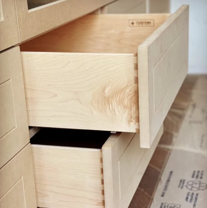 Close-up of an open drawer in a wooden dresser showing the unfinished natural wood interior.