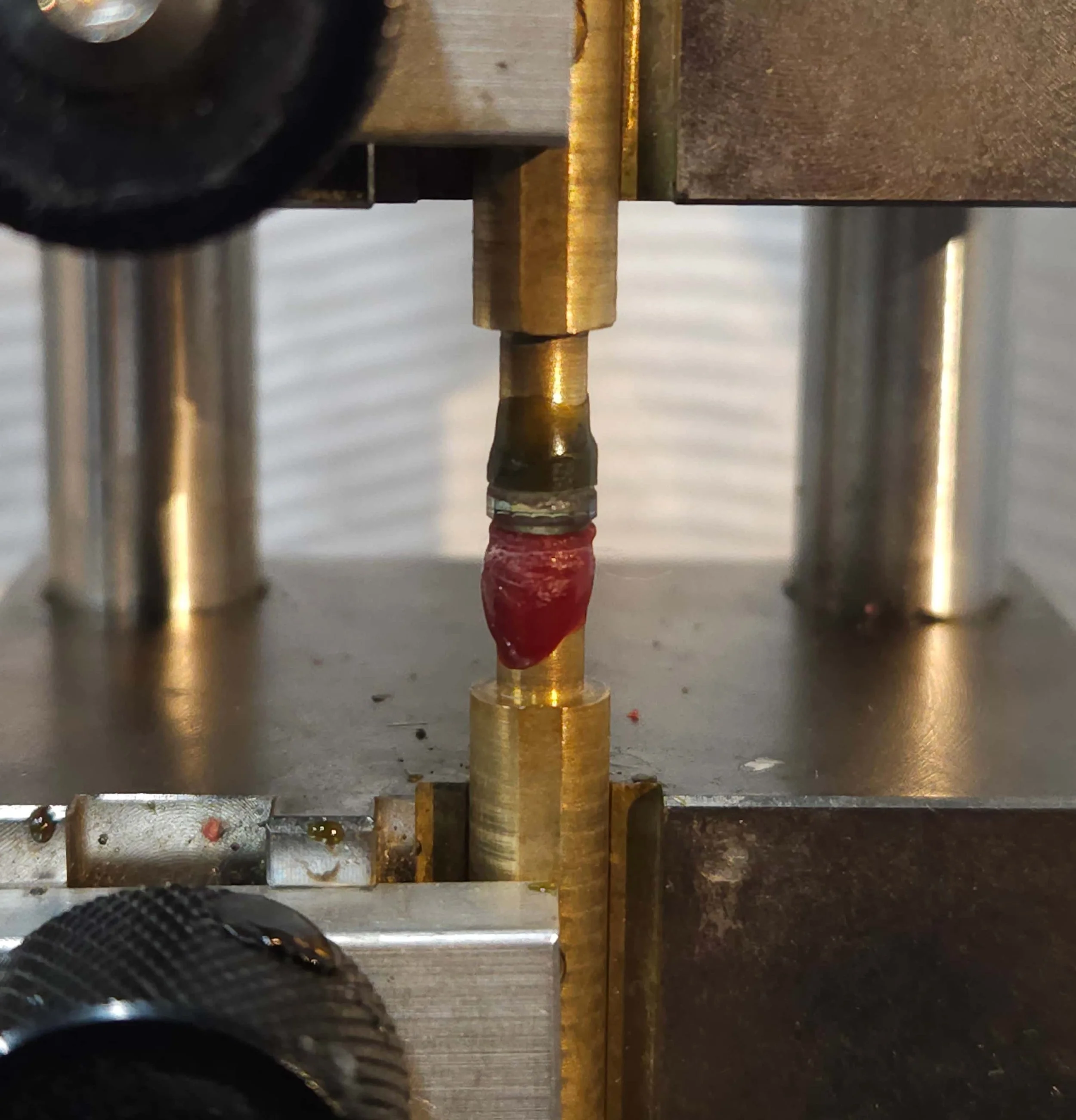 Close-up of a gemstone being transferred between two brass dops on a metal transfer jig.