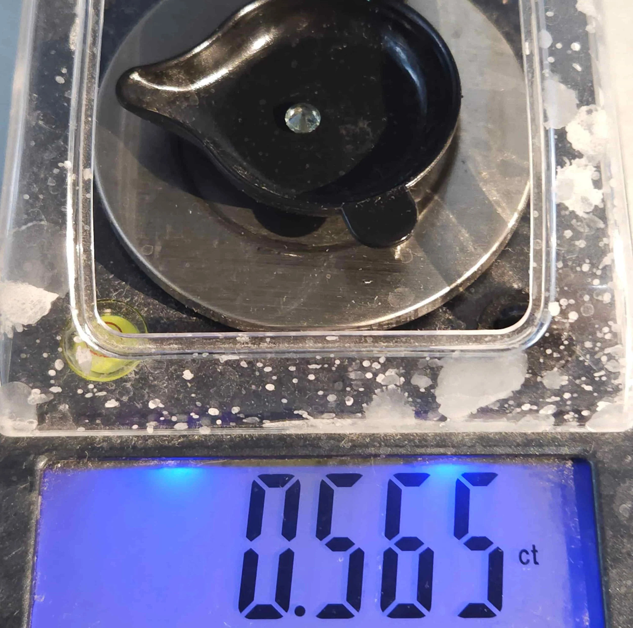 close-up image of a sapphire gemstone being measured on a lab scale showing 0.565ct.