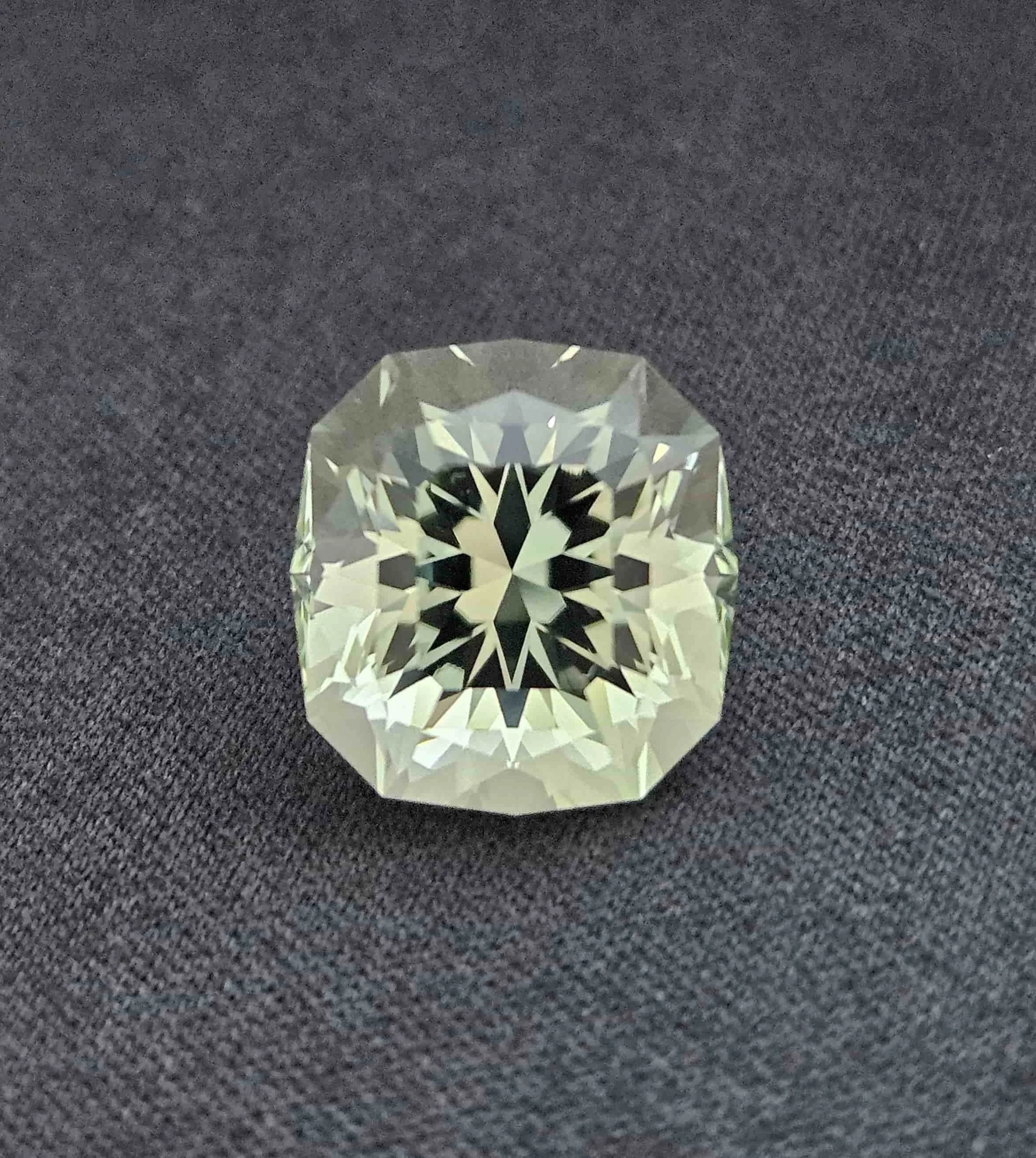 A cut diamond gemstone placed on a dark, textured surface.