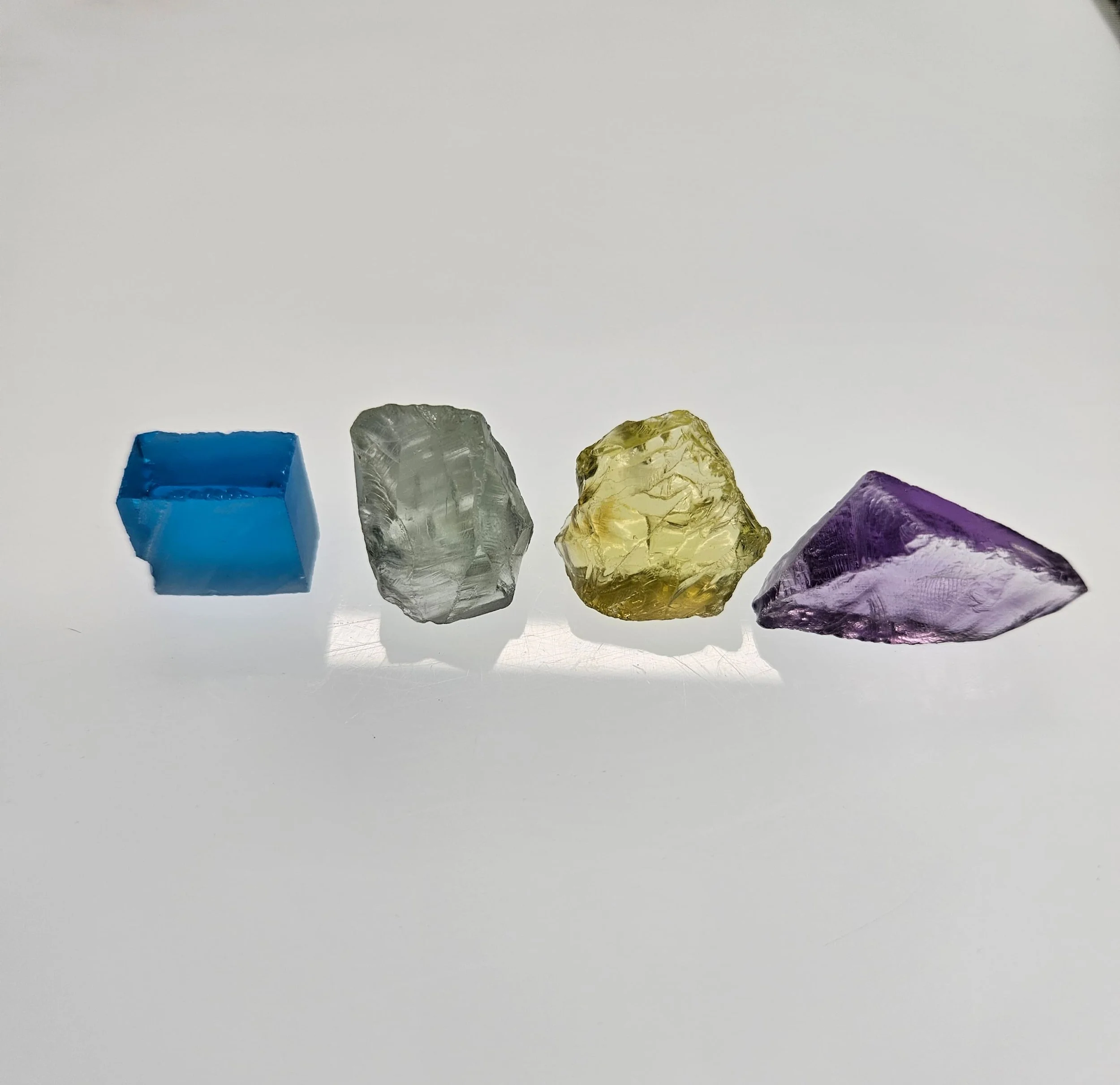 4 different rough quartz specimens resting on a light table