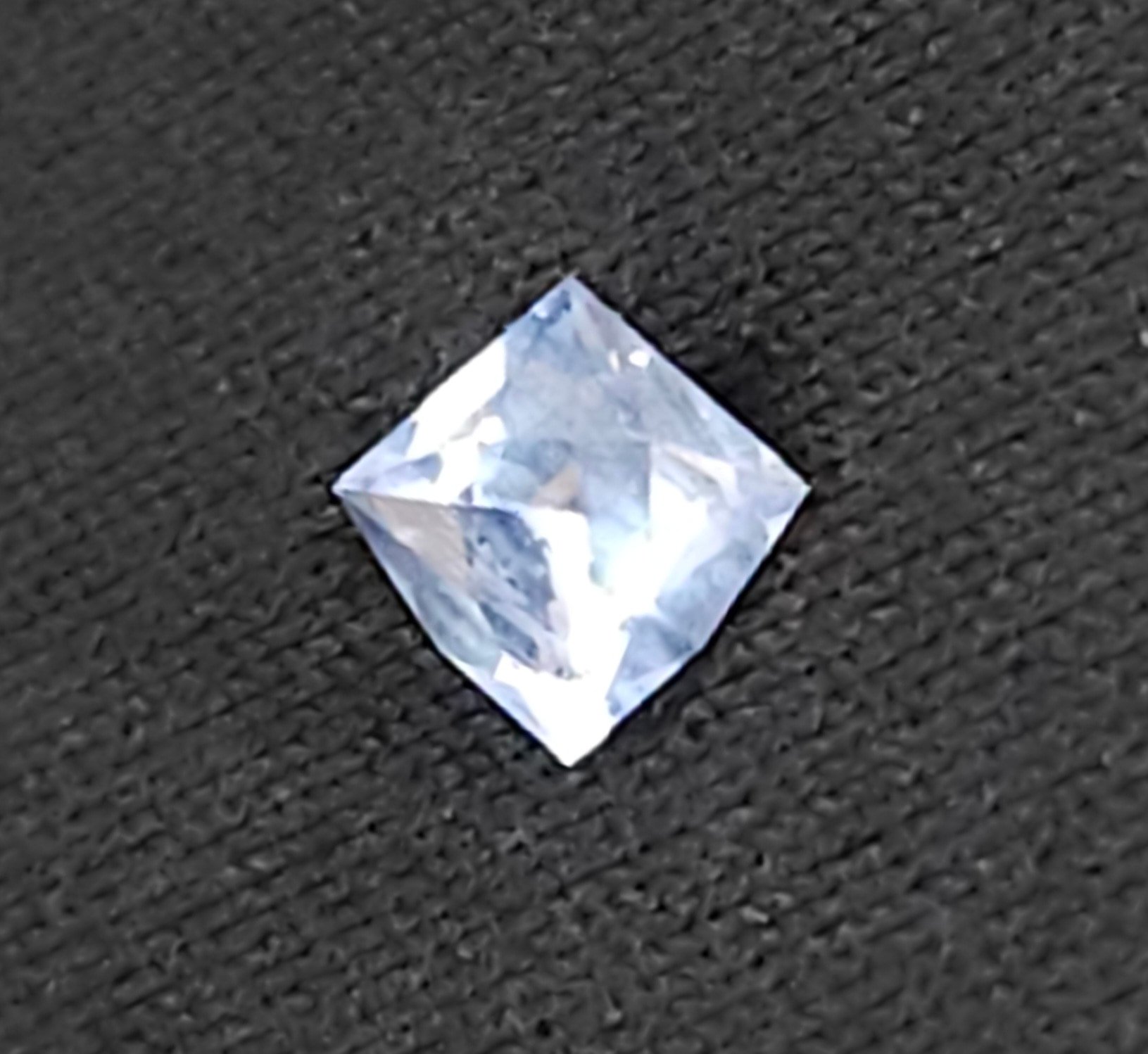 A precision faceted sky blue Montana sapphire on a textured black surface.