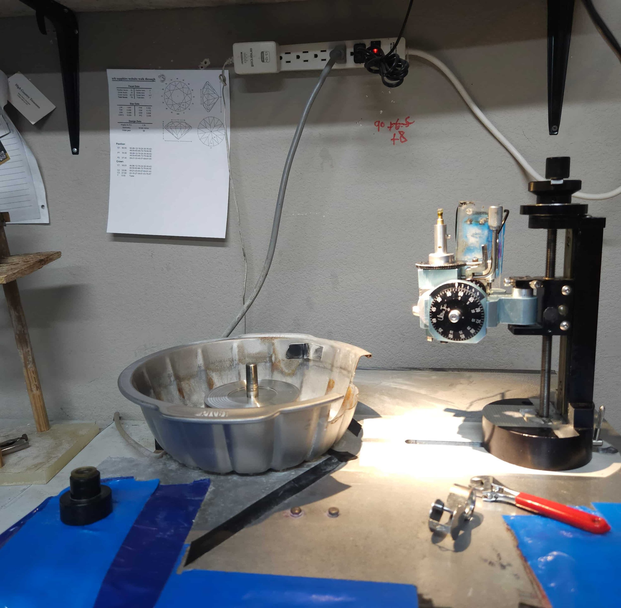 A faceting station with a gem diagram pinned to the wall in the background.