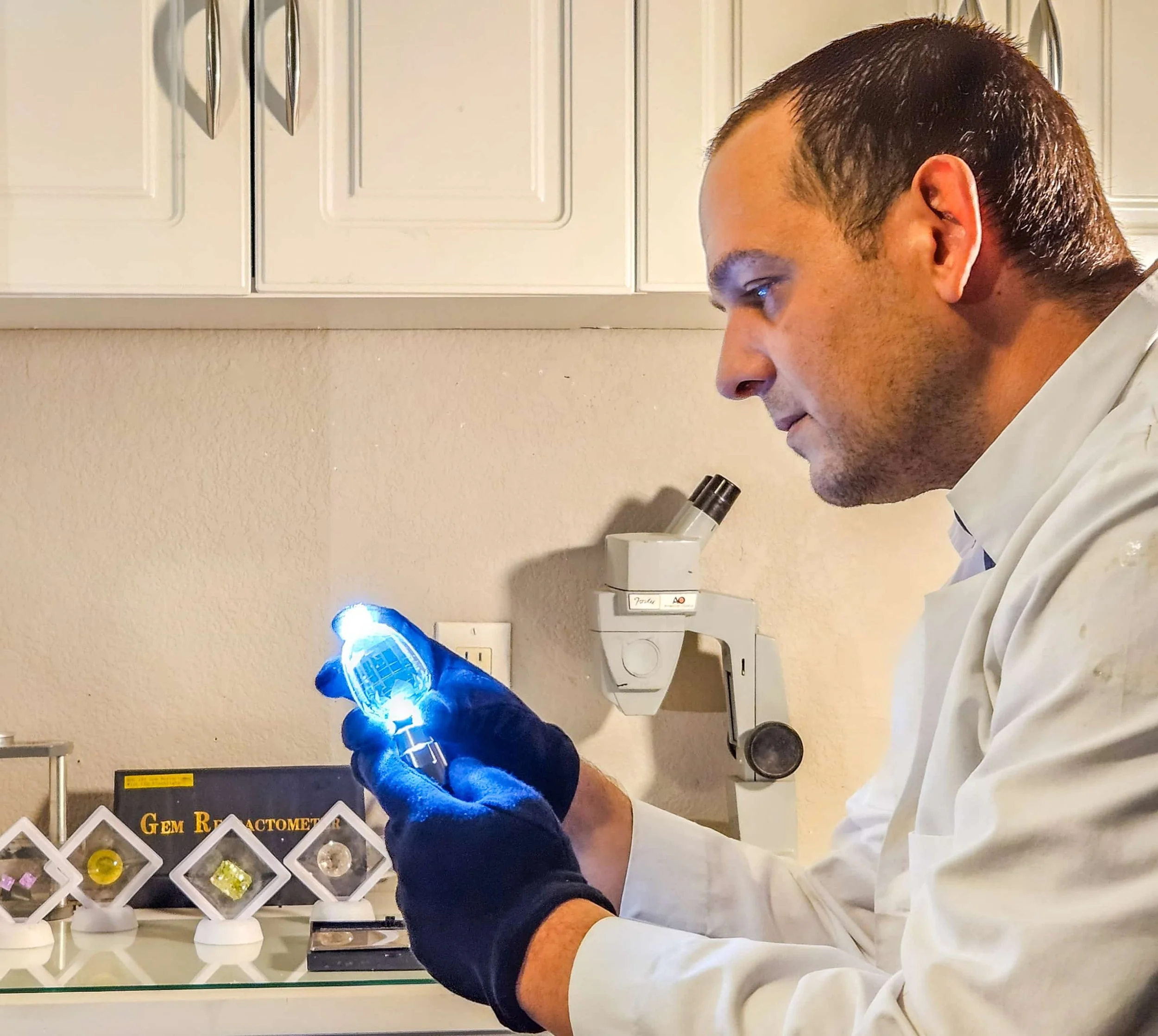 Scientist examining a gemstone sample using a flashlight in a laboratory.