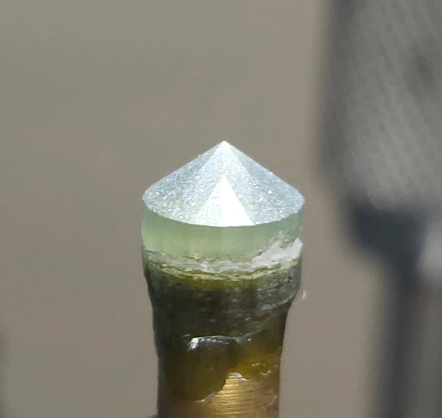 Close-up of a Montana Sapphire that has been faceted at 250 grit on the end of a brass dop.