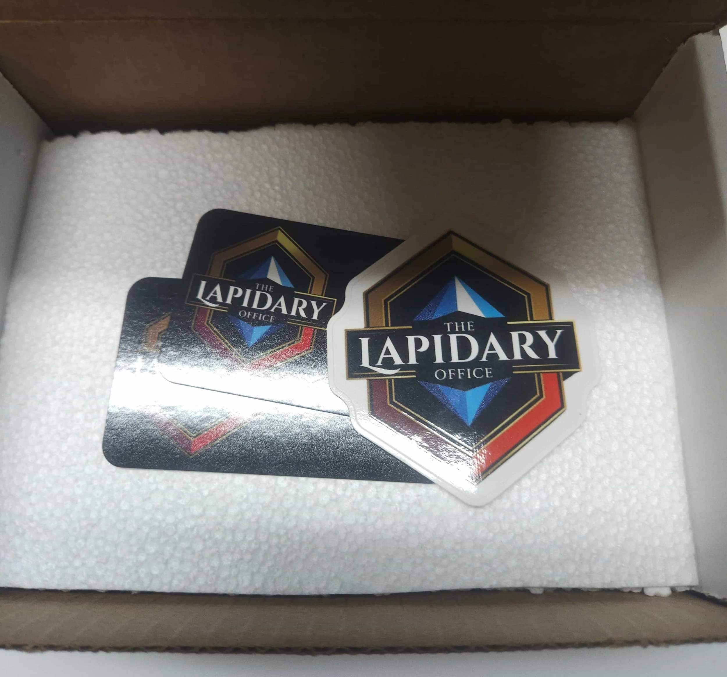 Cards from The Rapid Office trading game stacked inside a cardboard box on white foam padding.