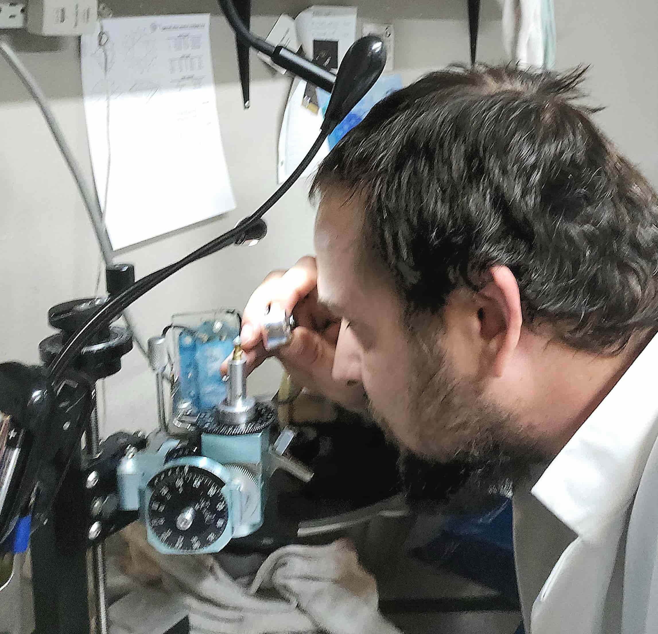 Ian Perry of The Lapidary Office inspecting a gemstone on his machine using a loupe.