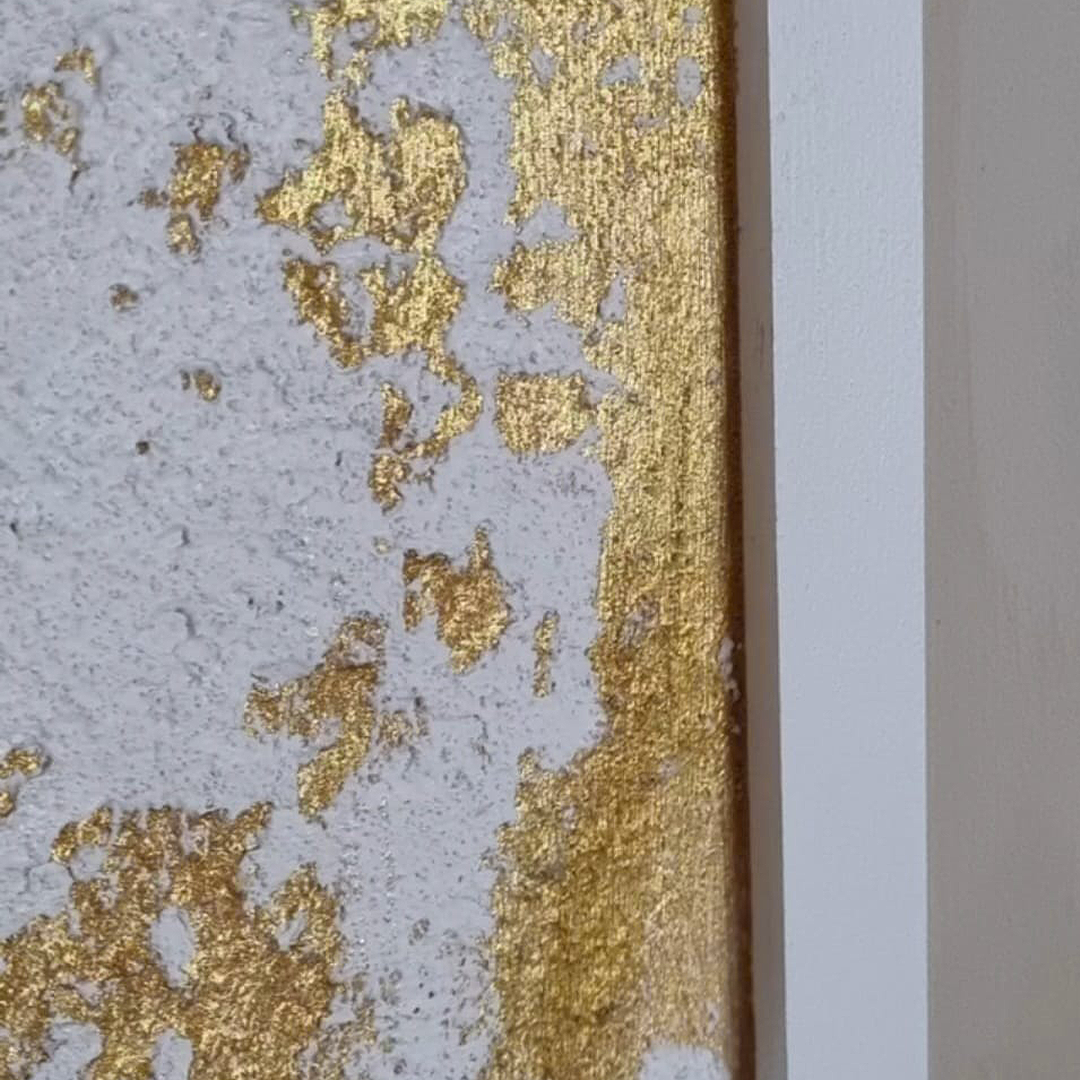 Close-up of a textured Venetian plastered wall with gold and white paint.