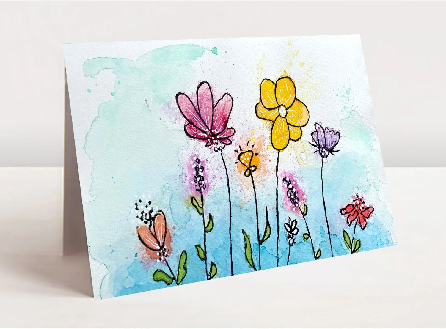 watercolor image of whimsical flowers on a greeting card mockup table