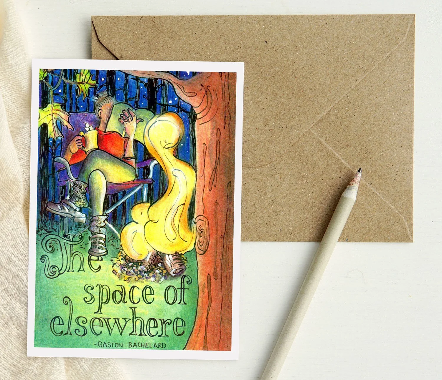 Illustrated greeting card with a woman sitting on a camp chair reading a book and drinking a mug of hot cocoa. There is a campfire in front of her and the trunk of a tree in the right side foreground. It is a nighttime scene with dark woods behind.