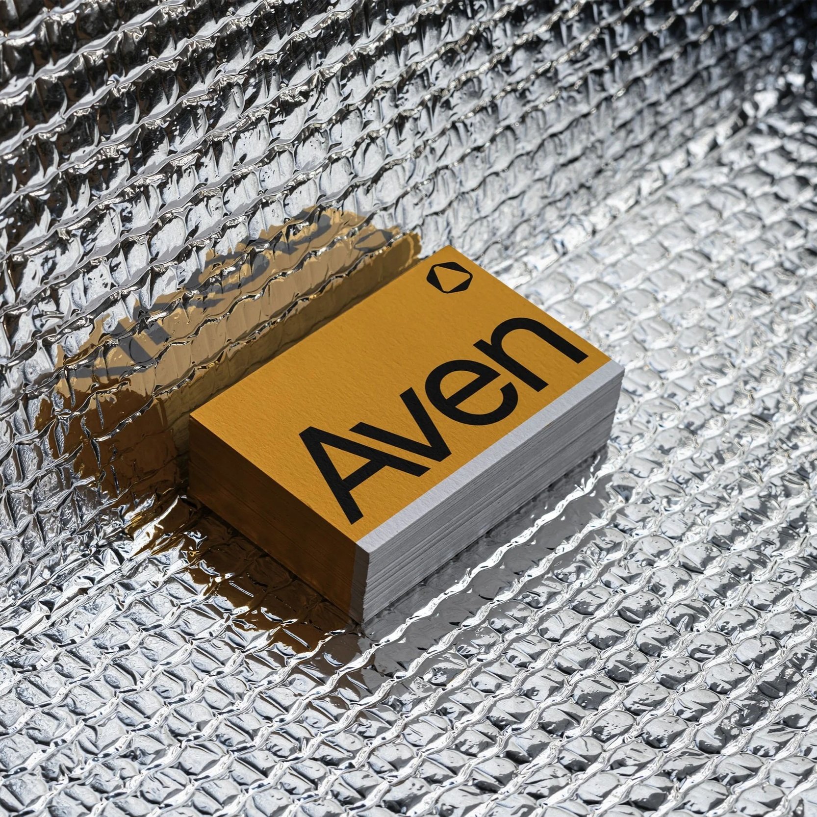 Nahaufnahme eines Stapels von gelben Fünf-Liter-Kanistern mit schwarzen Bezeichnungen, auf einem metallischen, reflektierenden Hintergrund aus Aluminiumfolie.