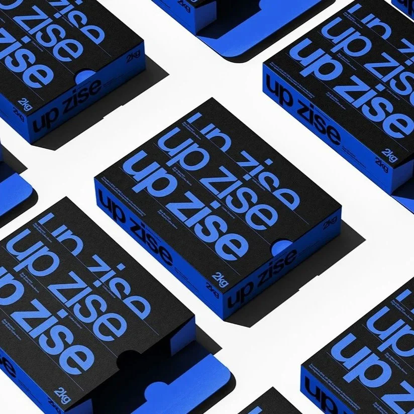 Mehrere schwarze und blaue Boxen mit der Aufschrift 'up size in zig' und '2kg' sind in einer Musteranordnung auf weißem Hintergrund angeordnet.