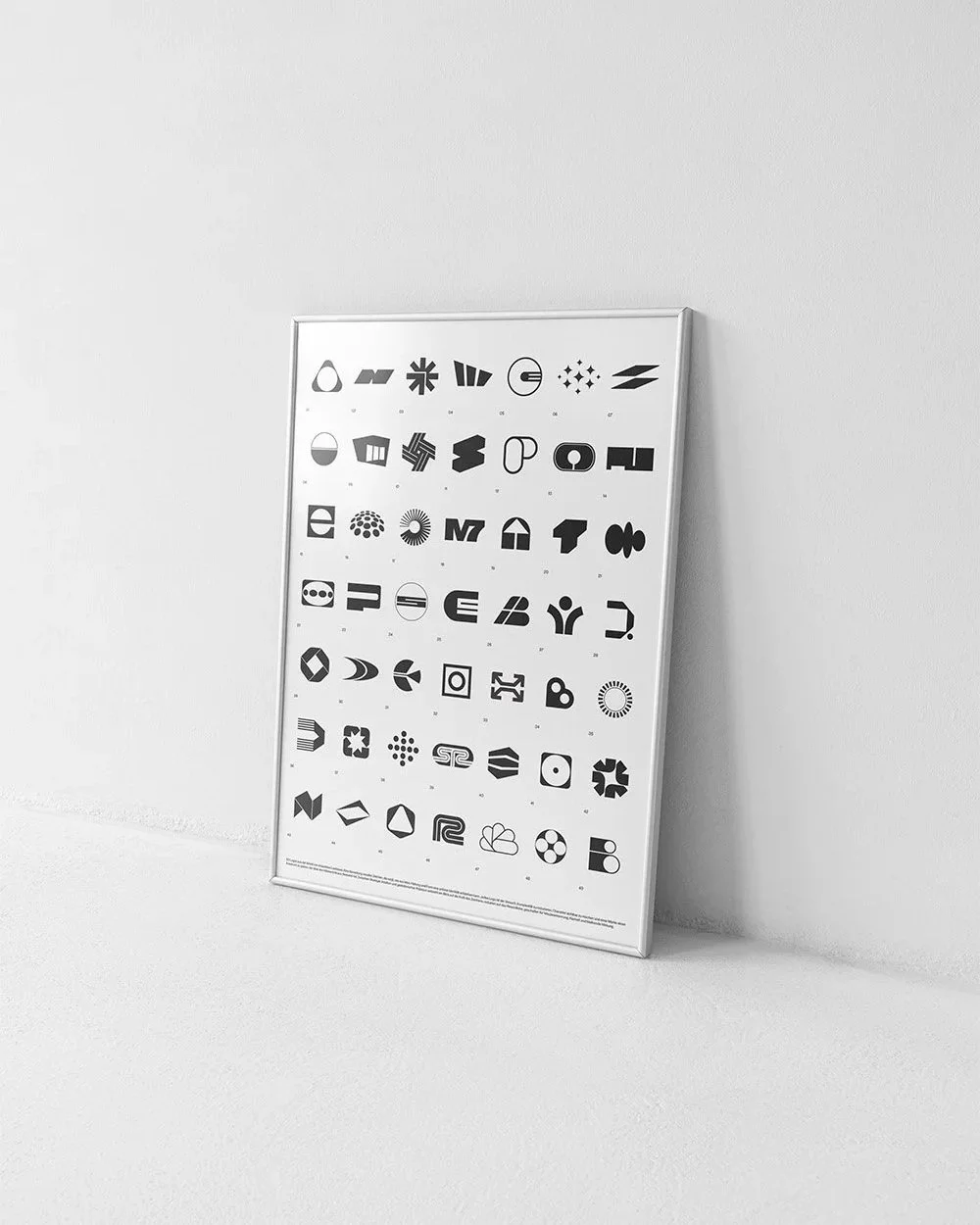 Schwarz-weiß-Poster mit verschiedenen geometrischen und abstrakten Symbolen, das an einer weißen Wand lehnt.