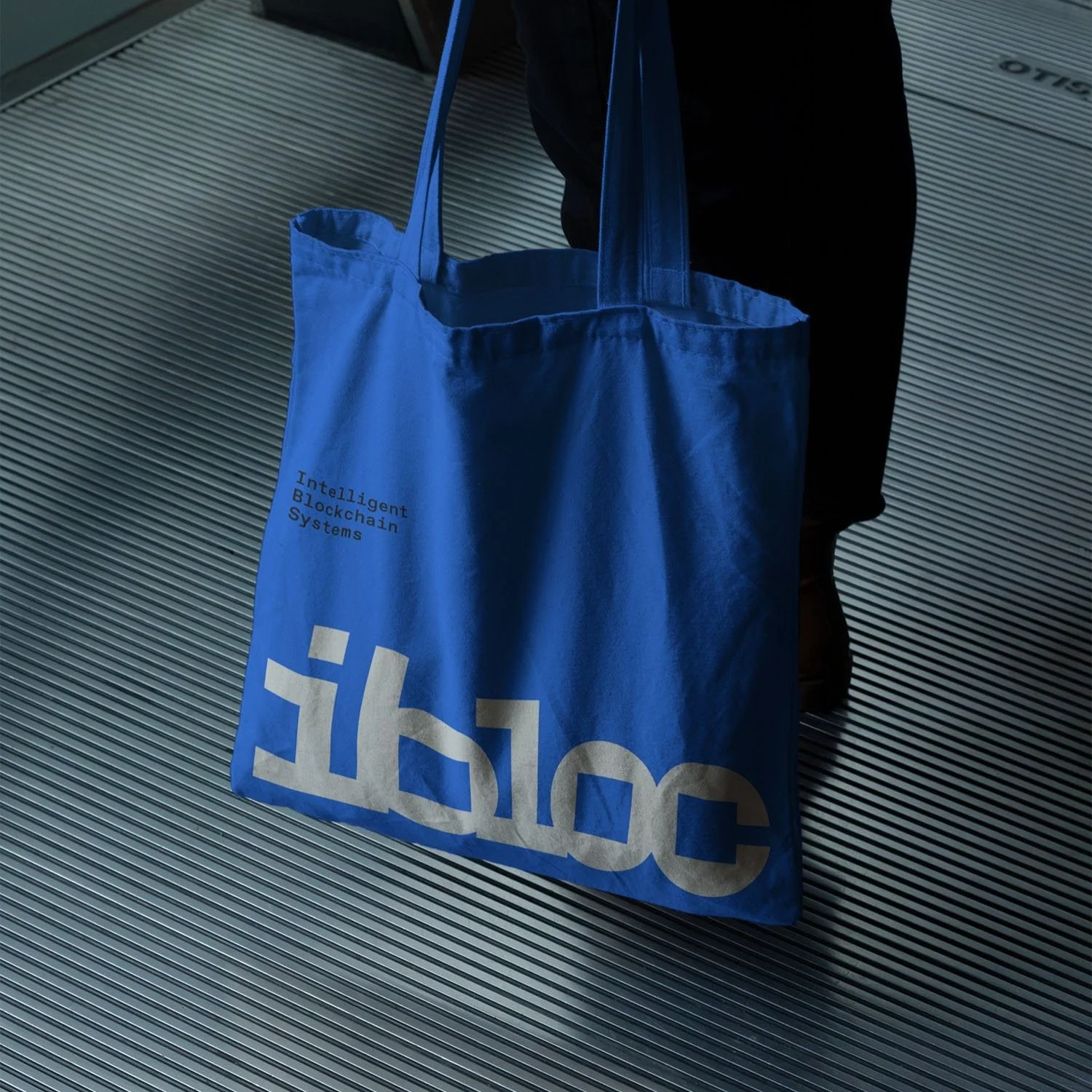 Blaue Einkaufstasche mit der Aufschrift 'IKEA' und dem Spruch 'Intelligent Blockchain Systems' auf einem metallischen Boden.