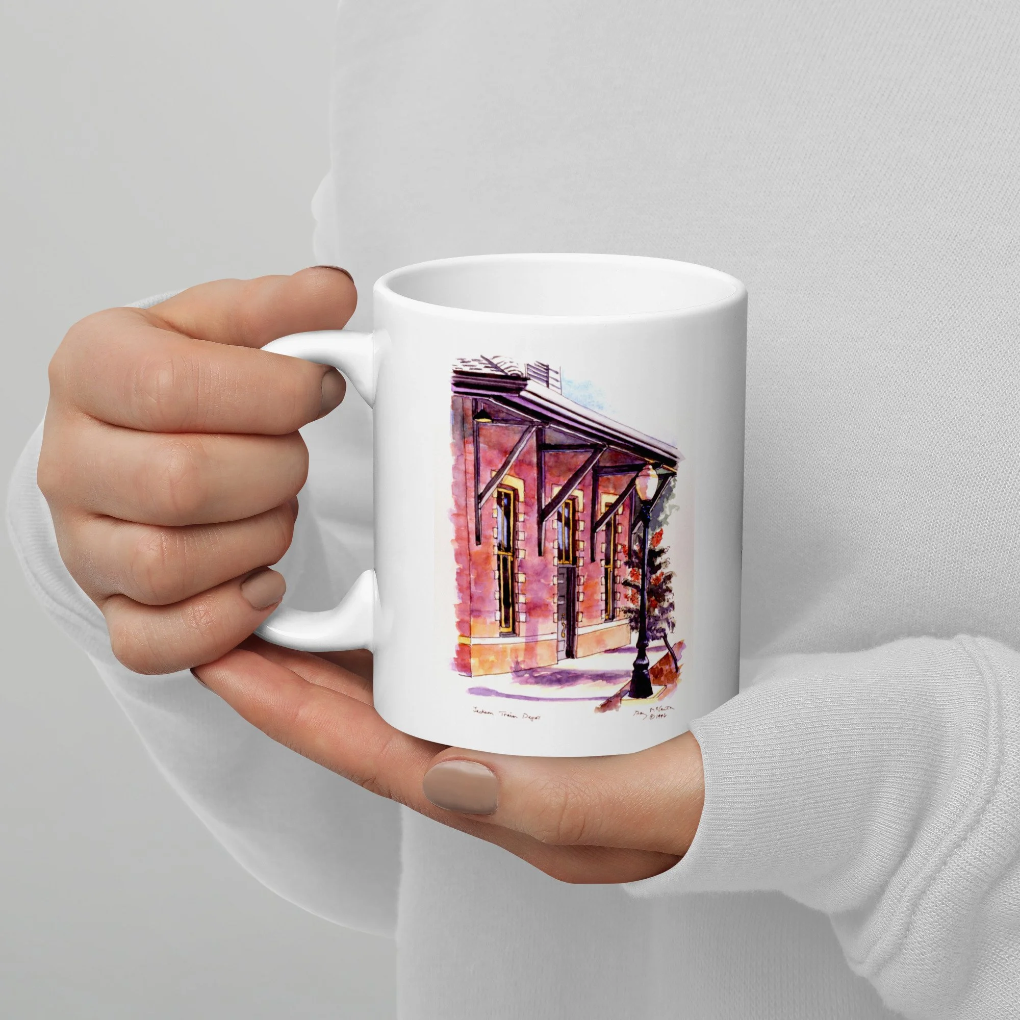11 oz white ceramic mug with Jackson Train Depot watercolor wrap by Beverly G. McCarter, Tennessee depot as portal of arrival in soft light.