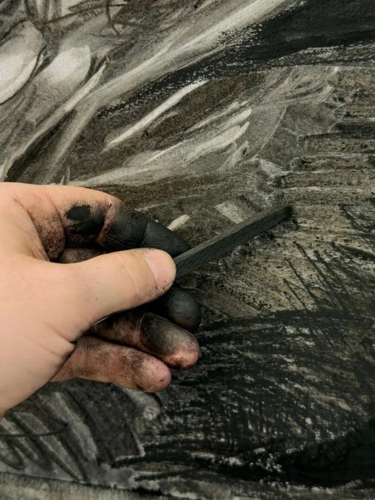 Artist hands covered in charcoal smudges during active mark-making – the unique personal handwriting that defines originality in drawing and painting.