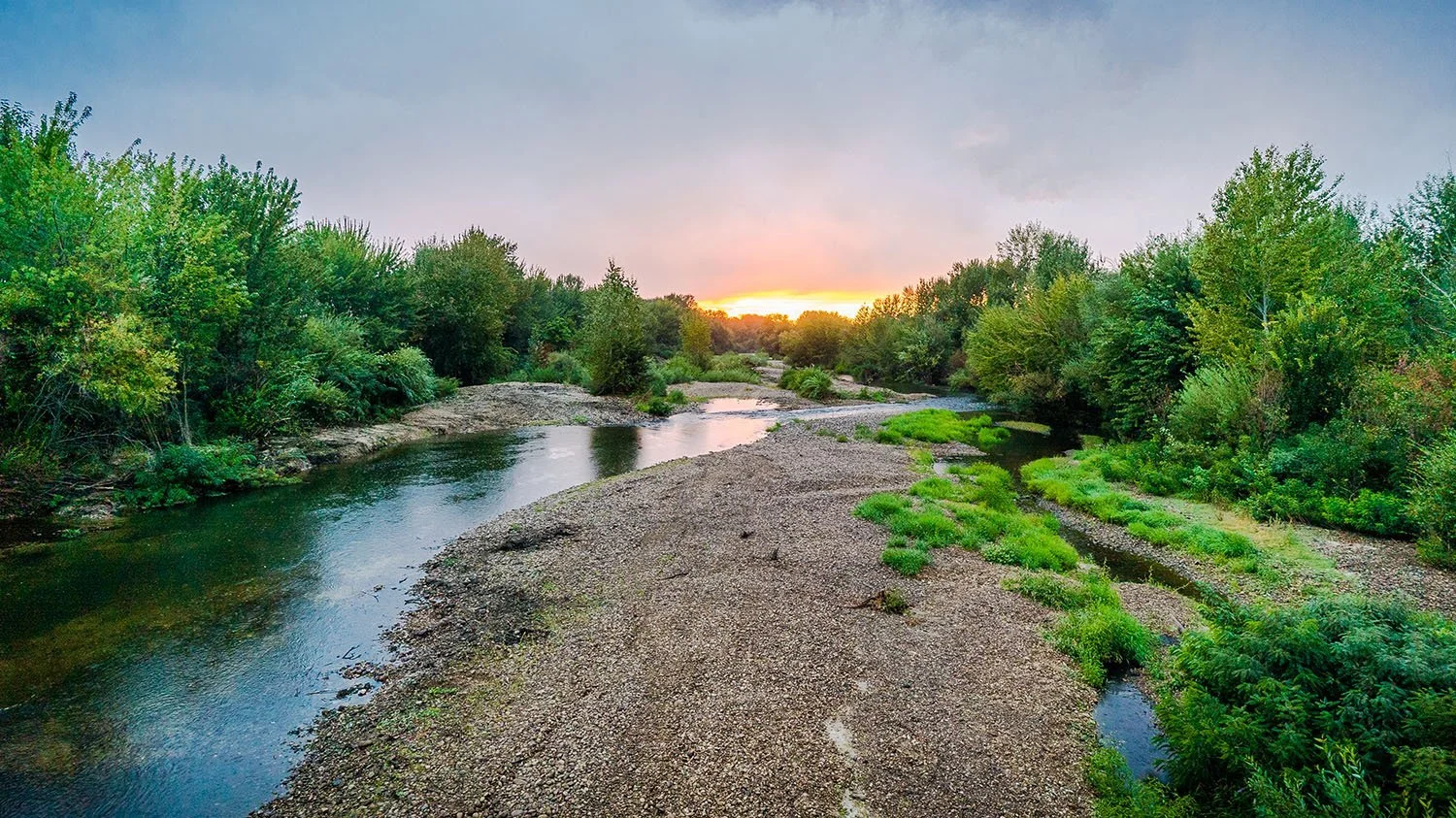Idaho sunset over the Boise river with greenery on both sides.