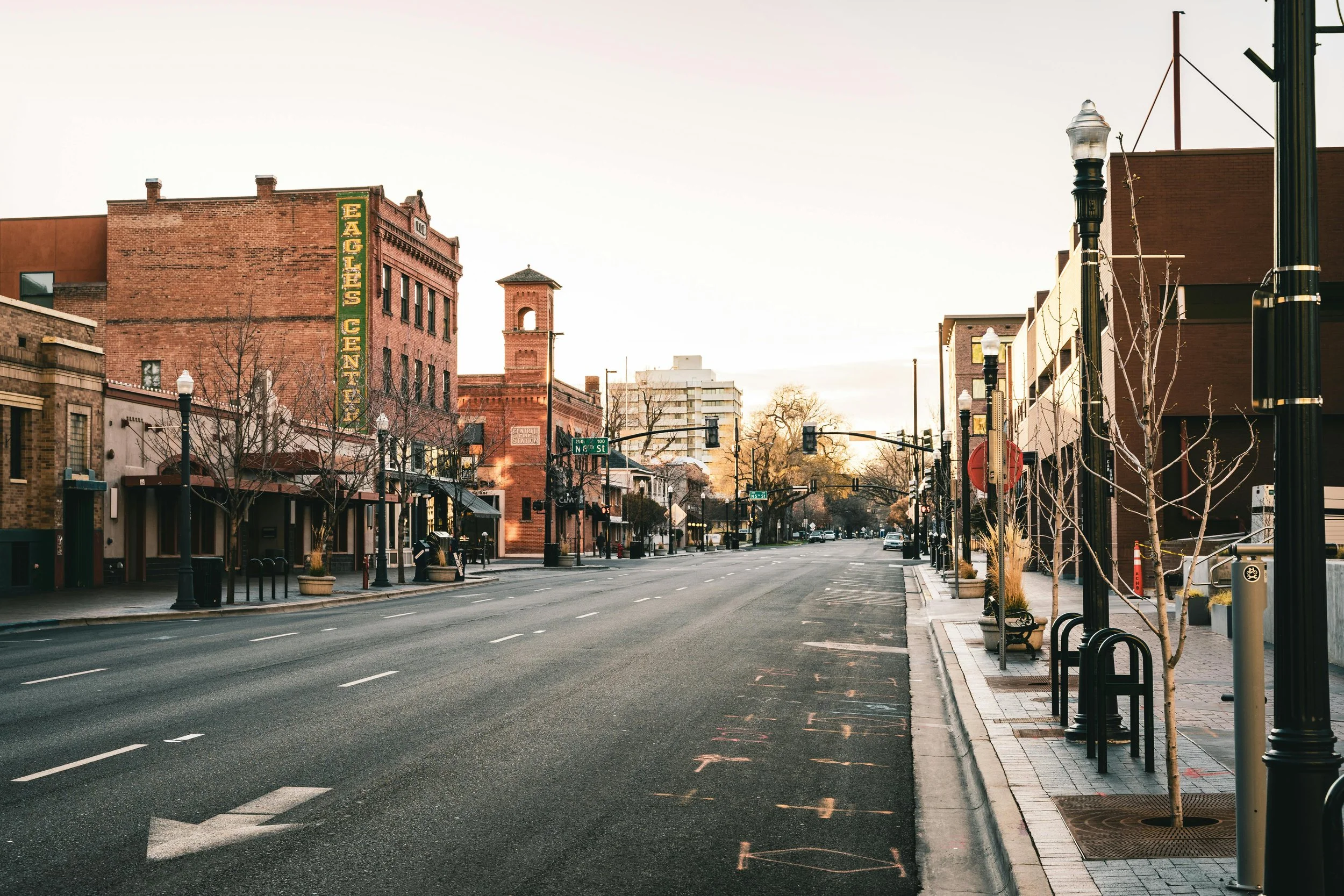An empty city street of Boise downtown with old brick buildings, trees, street lamps.