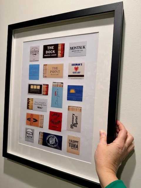 Artistic portrait of a person's face with abstract red and black paint strokes, framed on a white wall.