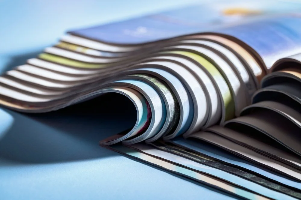 Open magazine with curled pages on a blue surface. Printing.