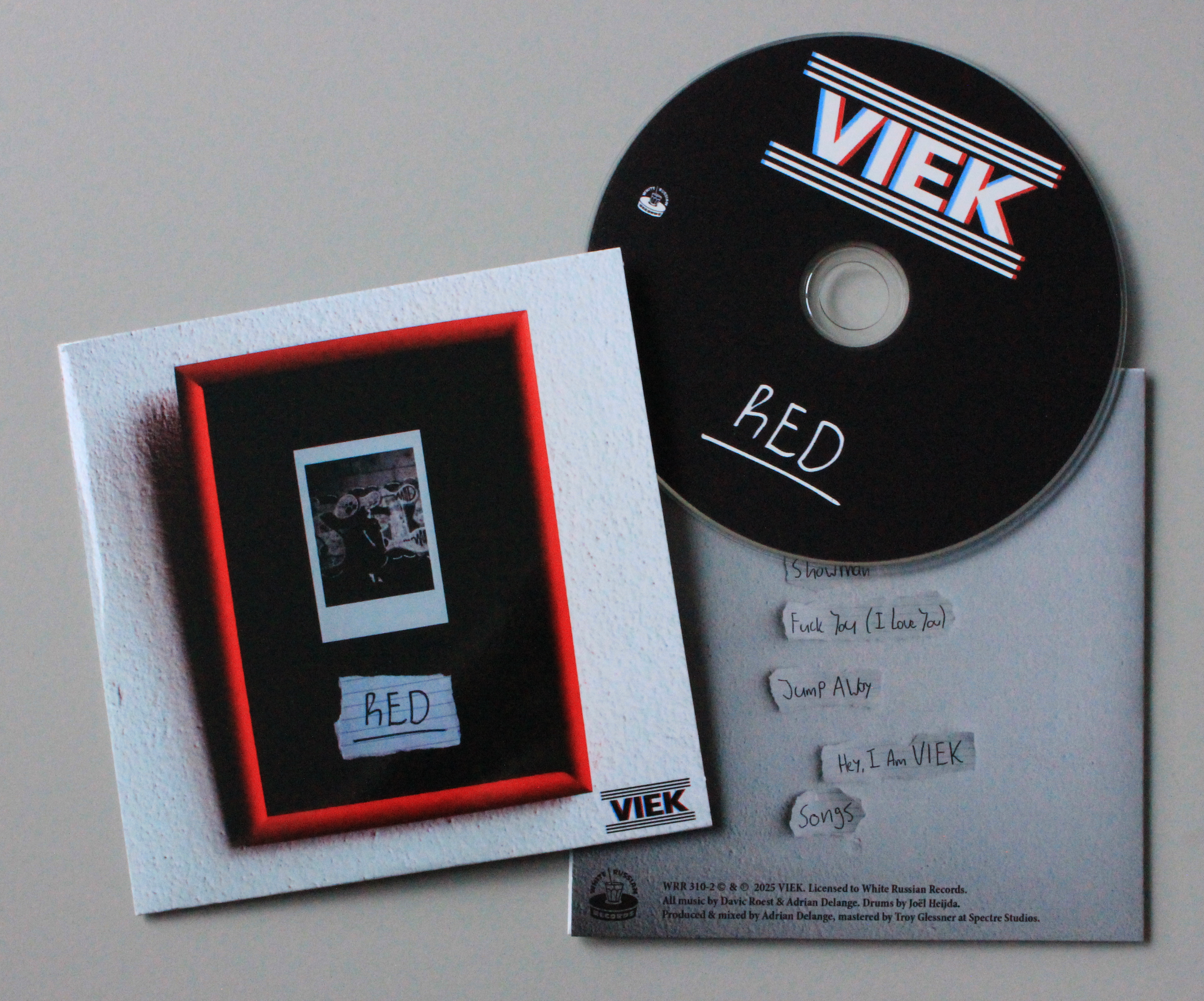 CD with the name 'VIEW' and the word 'RED' written on it, artwork featuring a black and white photo and a red border, handwritten tracklist on paper, and VIEK logo.