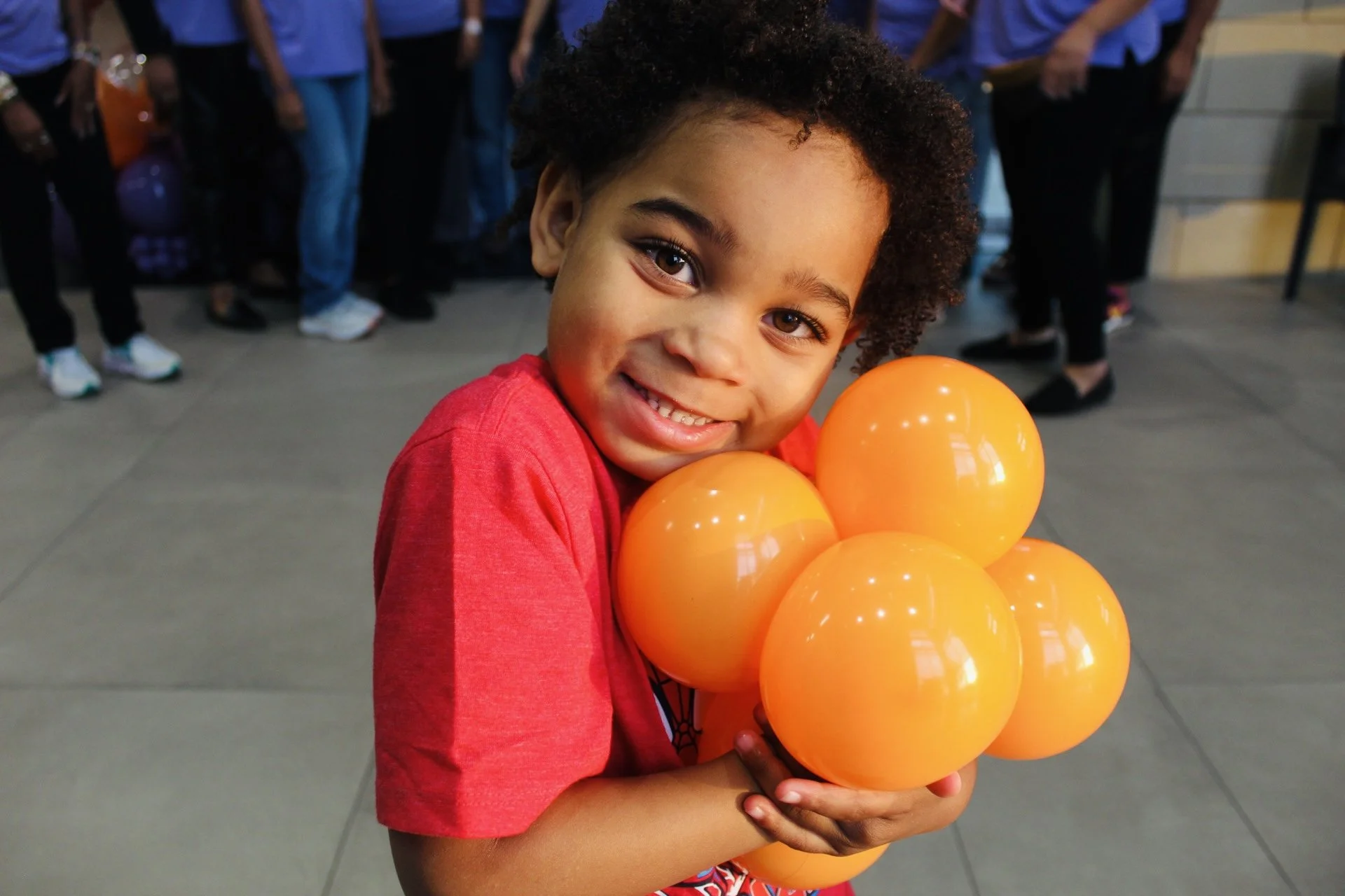 Decorative cupcakes with turquoise and purple swirl frosting and cake pops in matching colors, displayed on a white tray at a party table with a blue tablecloth and other desserts.