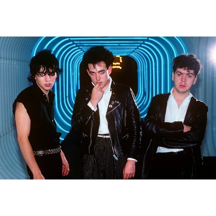 Black-clad young adults posing in a neon-lit tunnel.