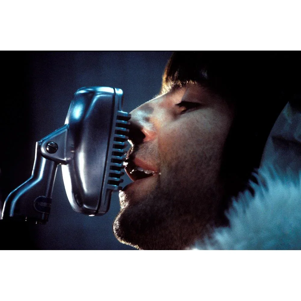 oasis-liam-gallagher-singing-into-microphone.webp