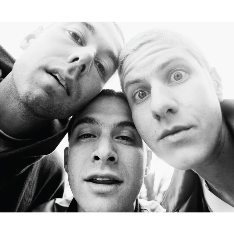 Three men taking a close-up selfie together, looking down at the camera, with surprised or amused expressions.