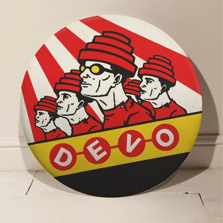 A circular graphic design with four stylized male faces with red striped hats, set against red and white diagonal stripes background. The bottom section has a yellow strip with the word "DEVO" written in red circles with white letters.