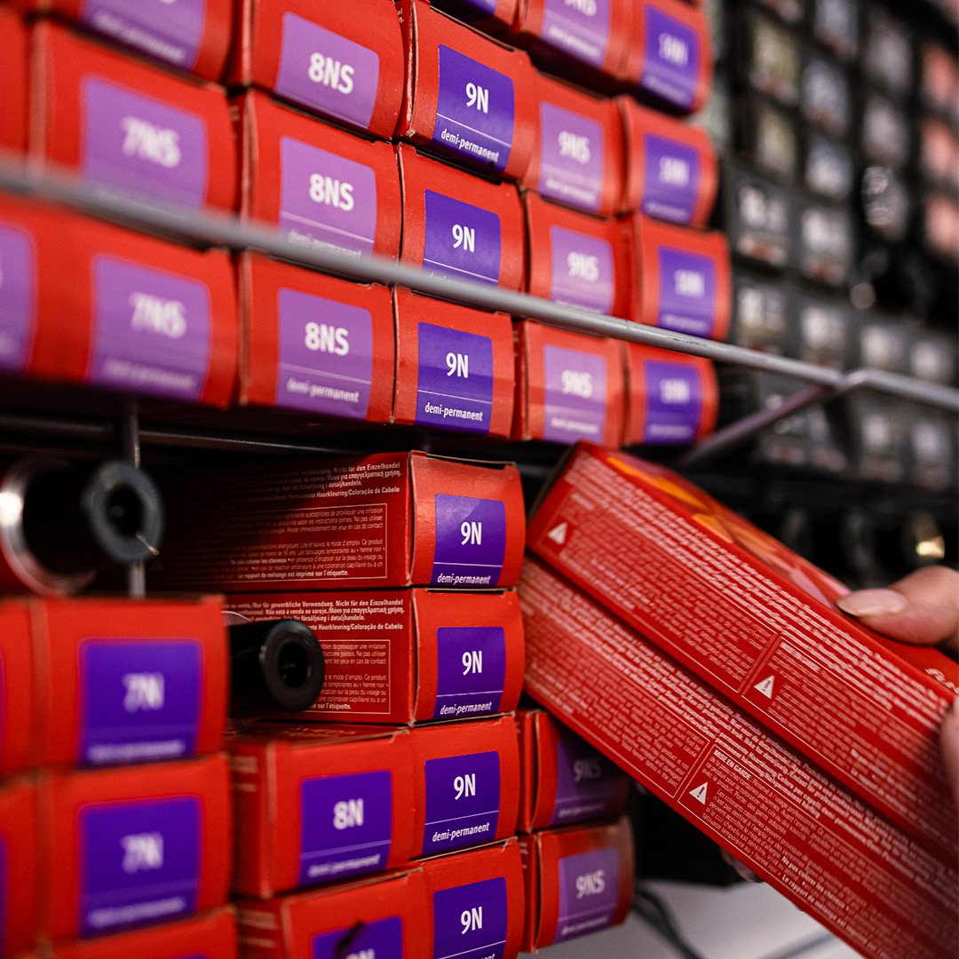 Shelf with multiple boxes of semi-permanent hair color labeled '9N' in purple and red packaging.