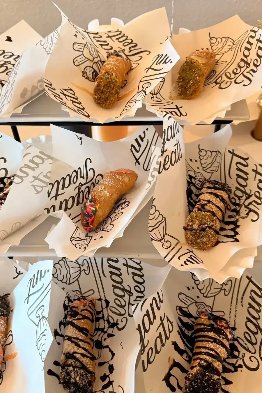 Plate of assorted cannoli desserts with different toppings and fillings at a bakery or dessert shop.