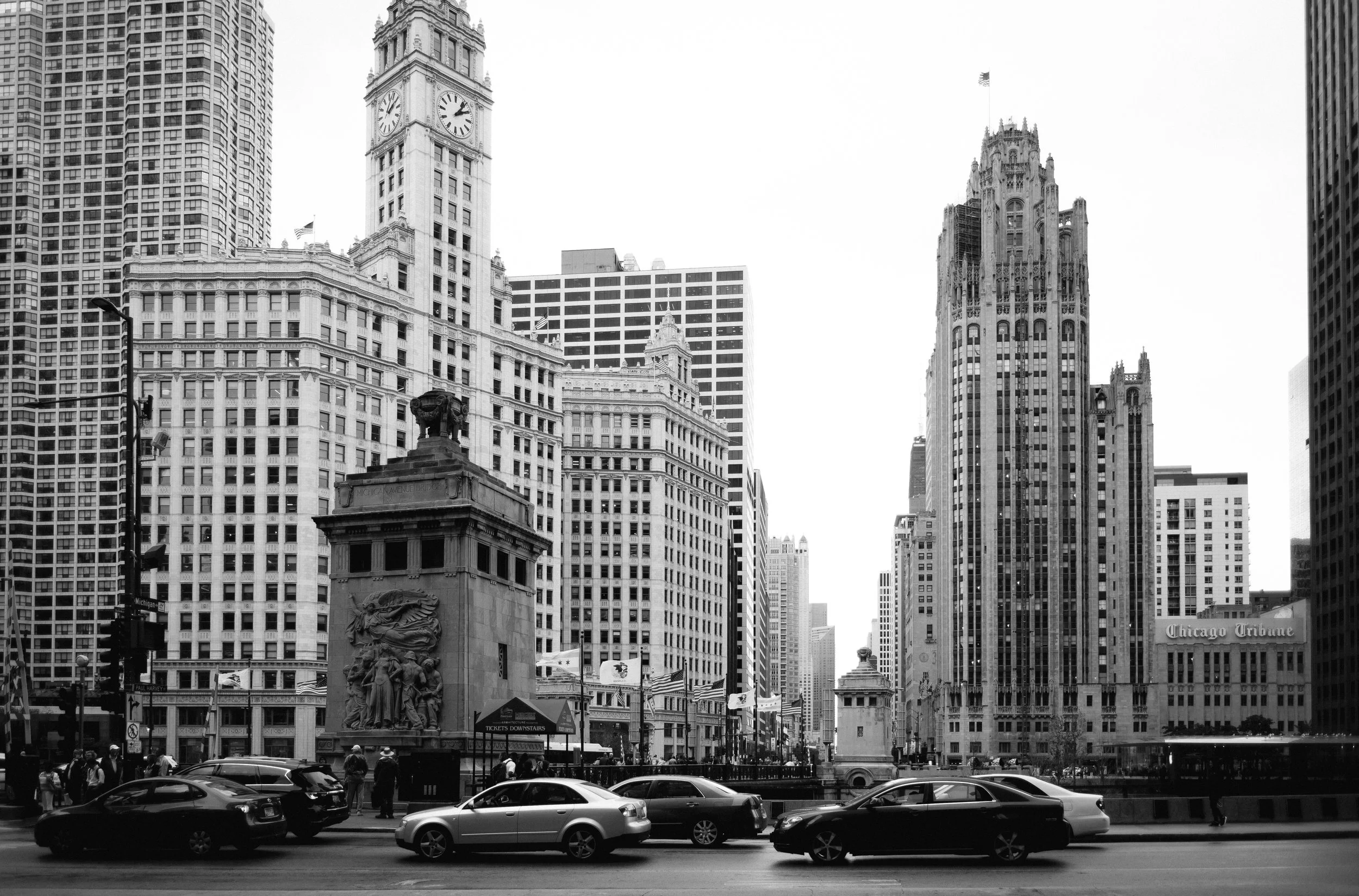 Black and white photo of Chicago cityscape with historical buildings, traffic, and pedestrians.