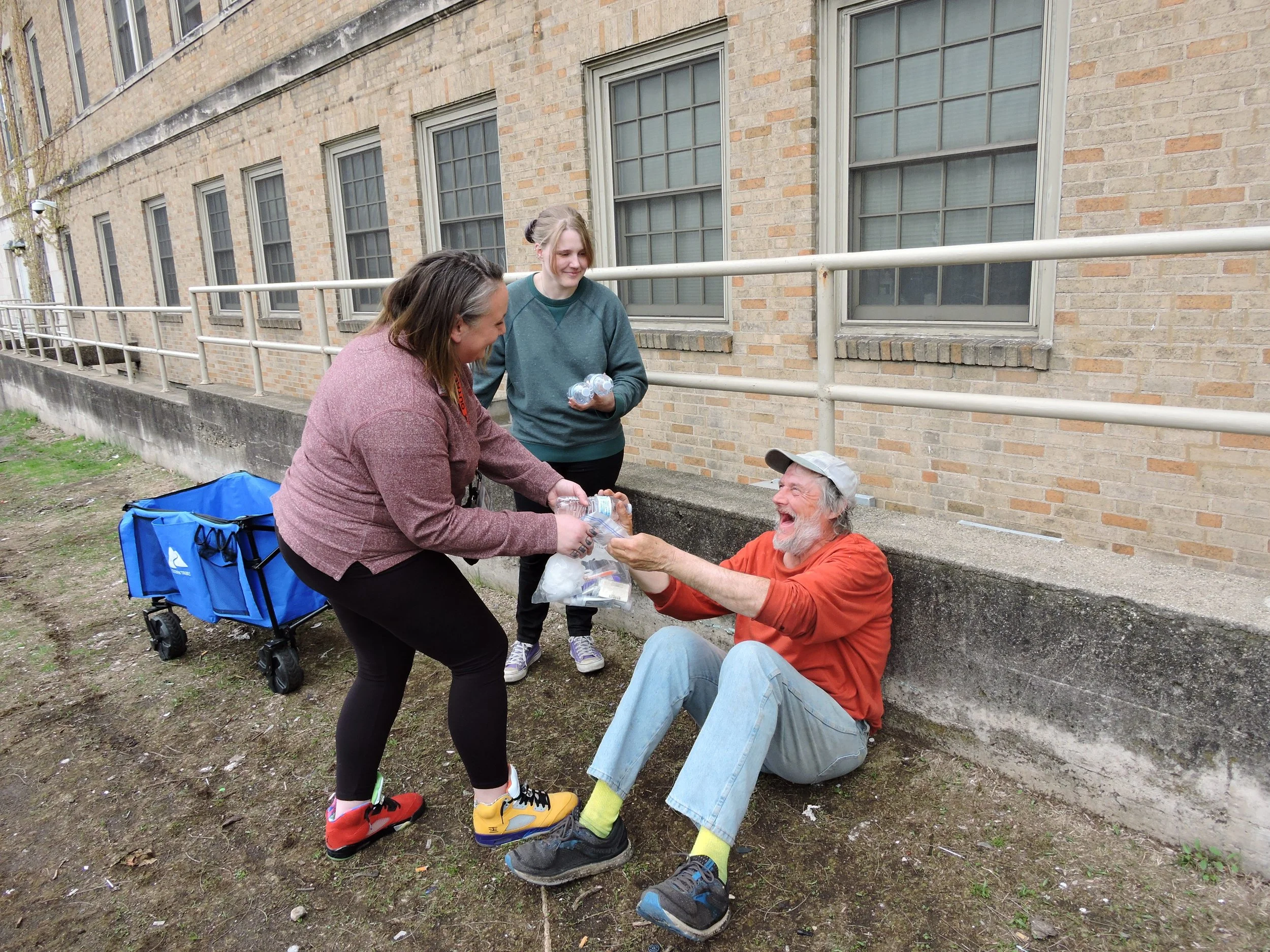 Services provided by our homeless outreach team. Photo shows an individual on the street receiving goods.