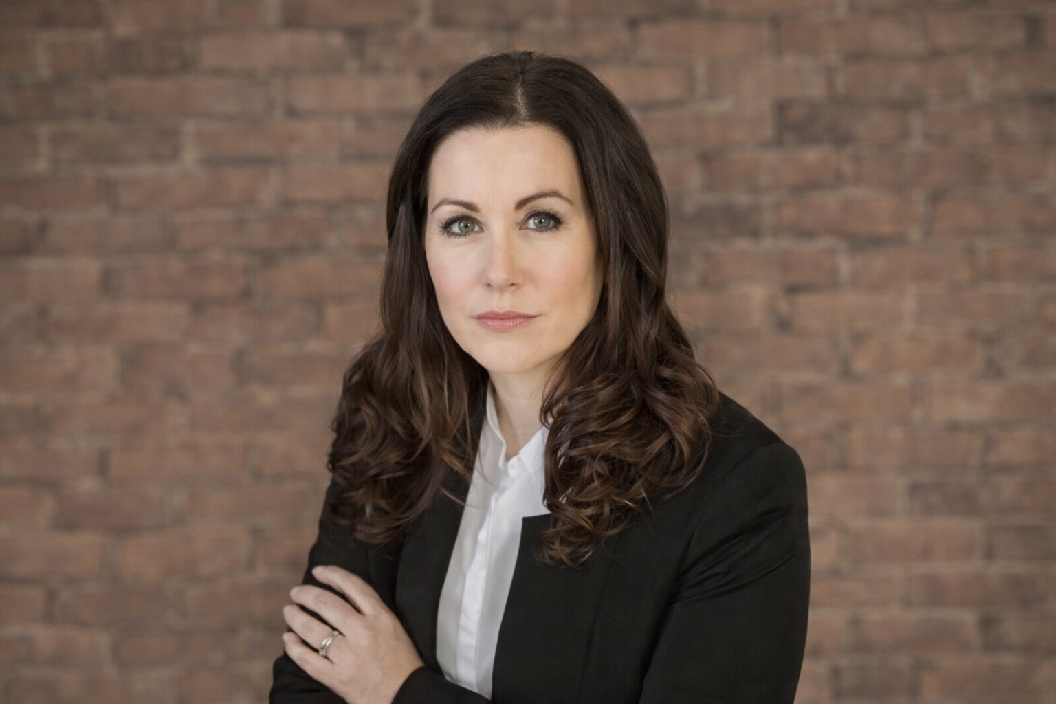 A young woman with shoulder-length black hair smiling in a lush green environment.
