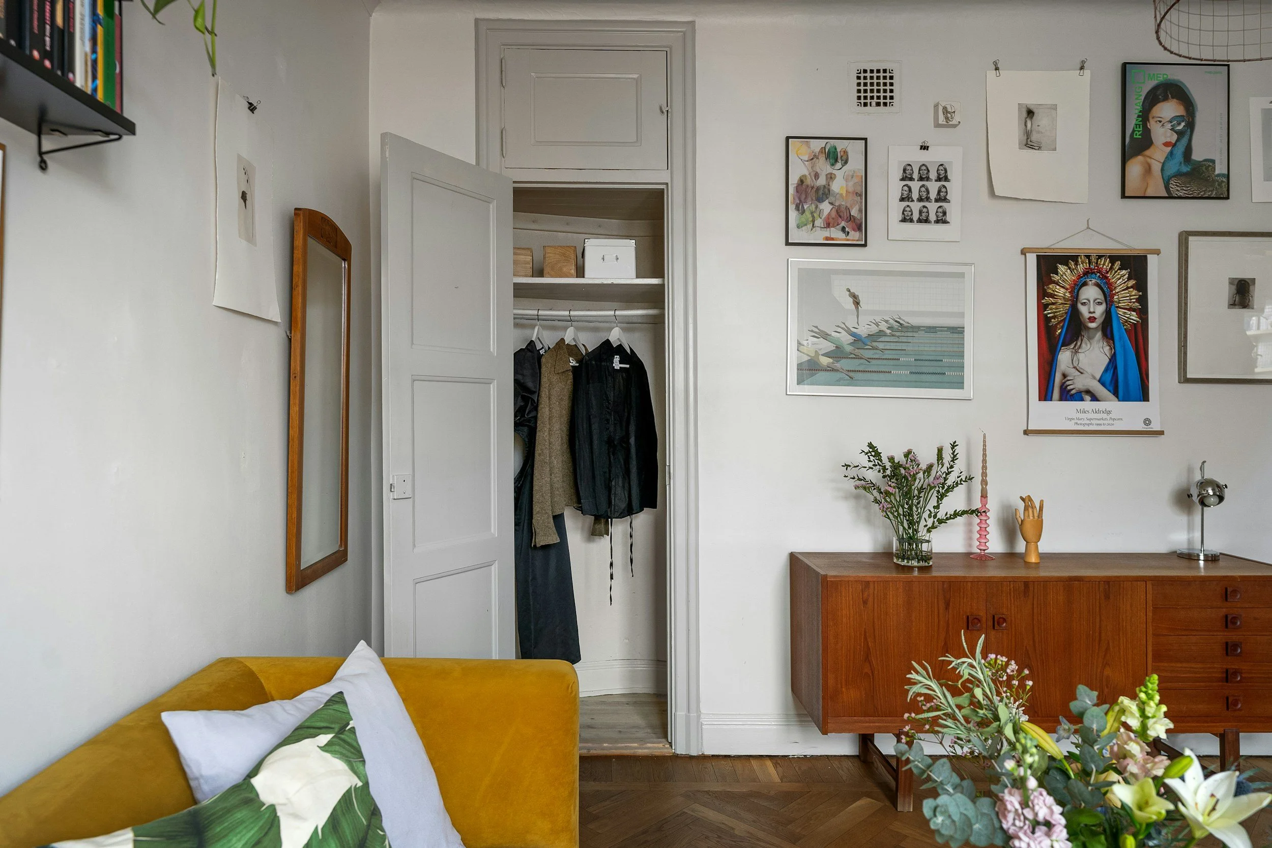 A light-filled room with a yellow couch, simple art on the wall, and an organized closet that keeps everything feeling fresh and uncluttered.