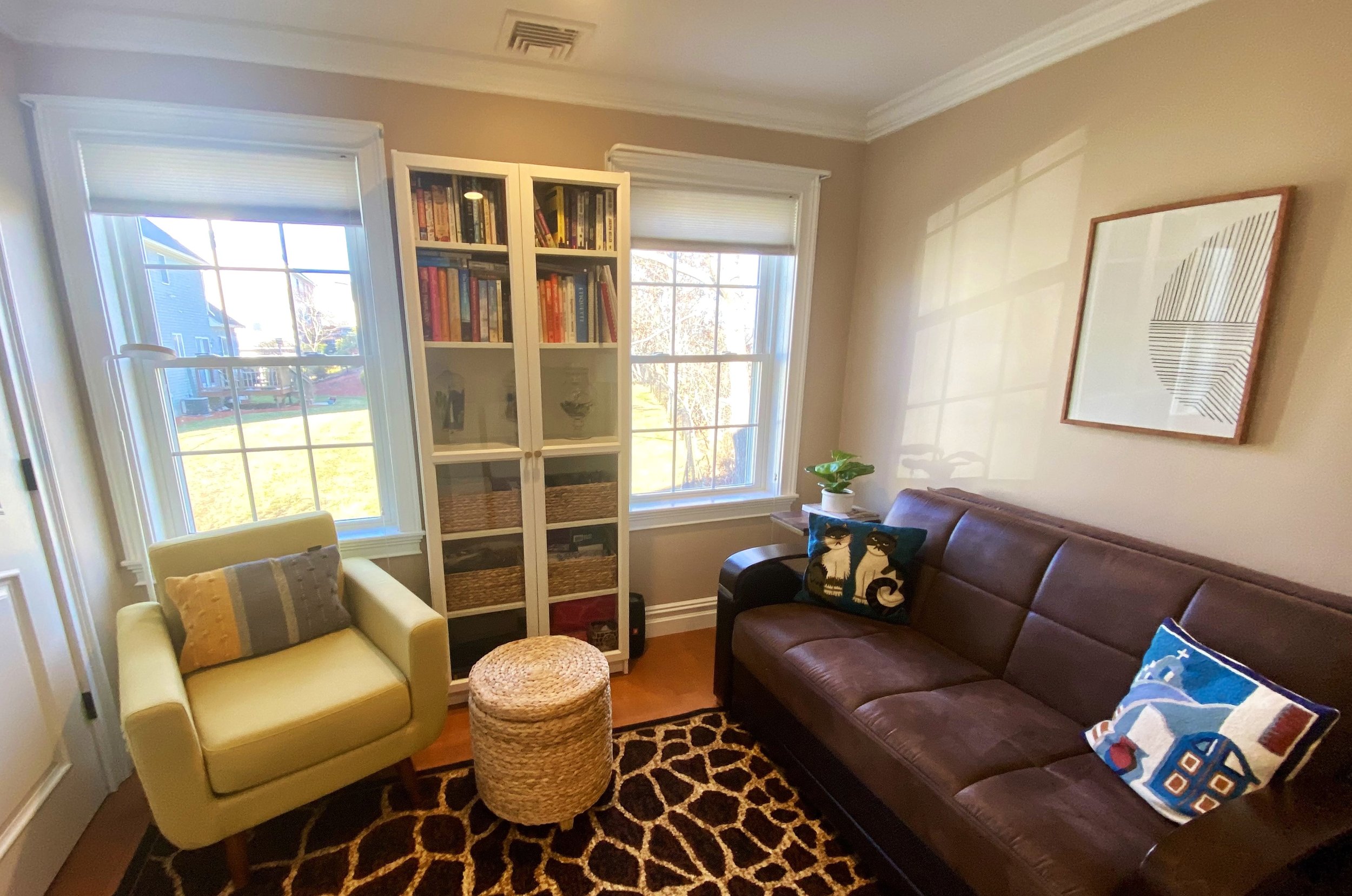 Light-filled home office and living space with organized book storage, cozy seating, and warm textures designed for focus and everyday comfort.