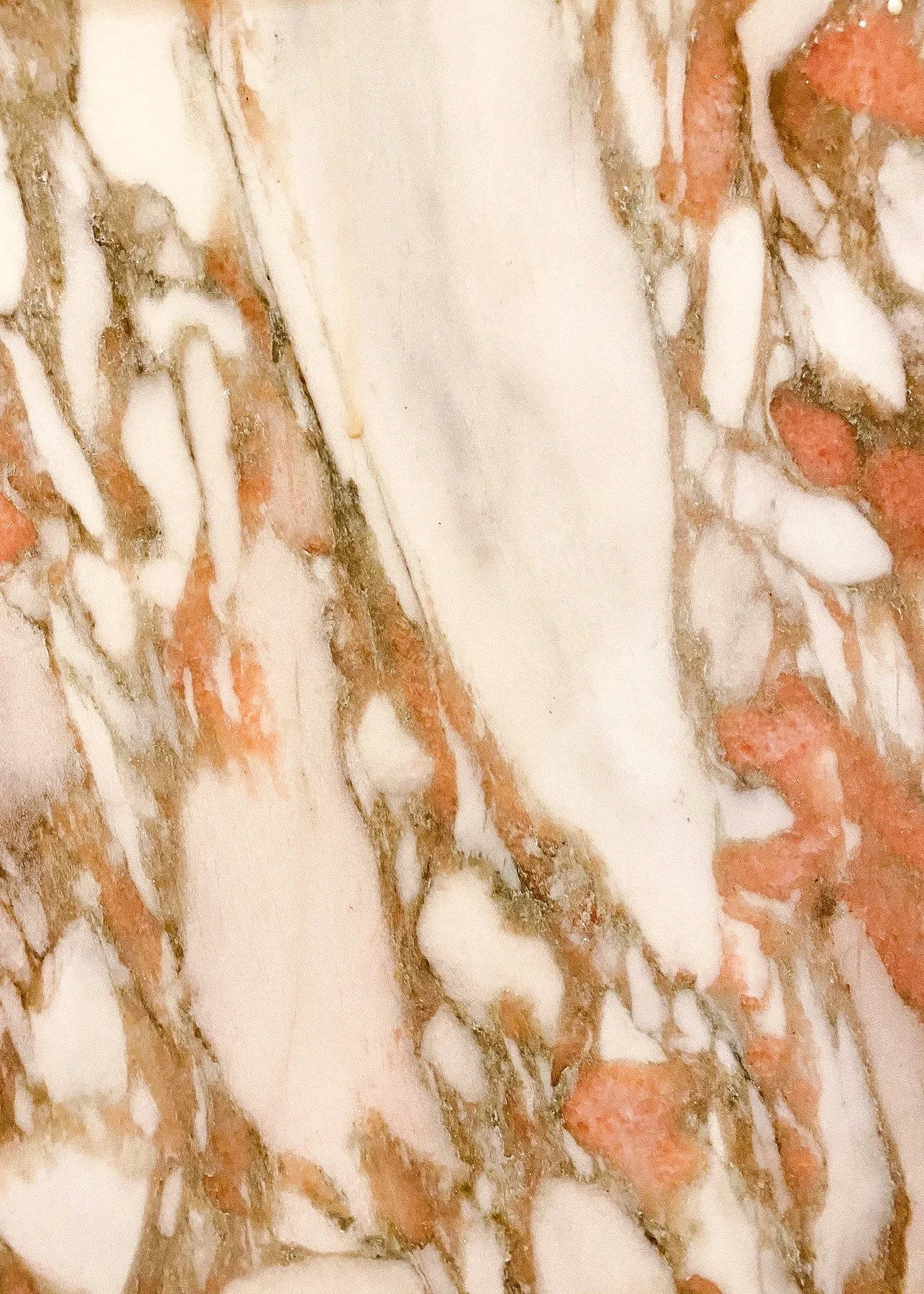 Close-up of a polished marble surface with a swirling pattern of white, pink, and brown veining. The texture is smooth and elegant.