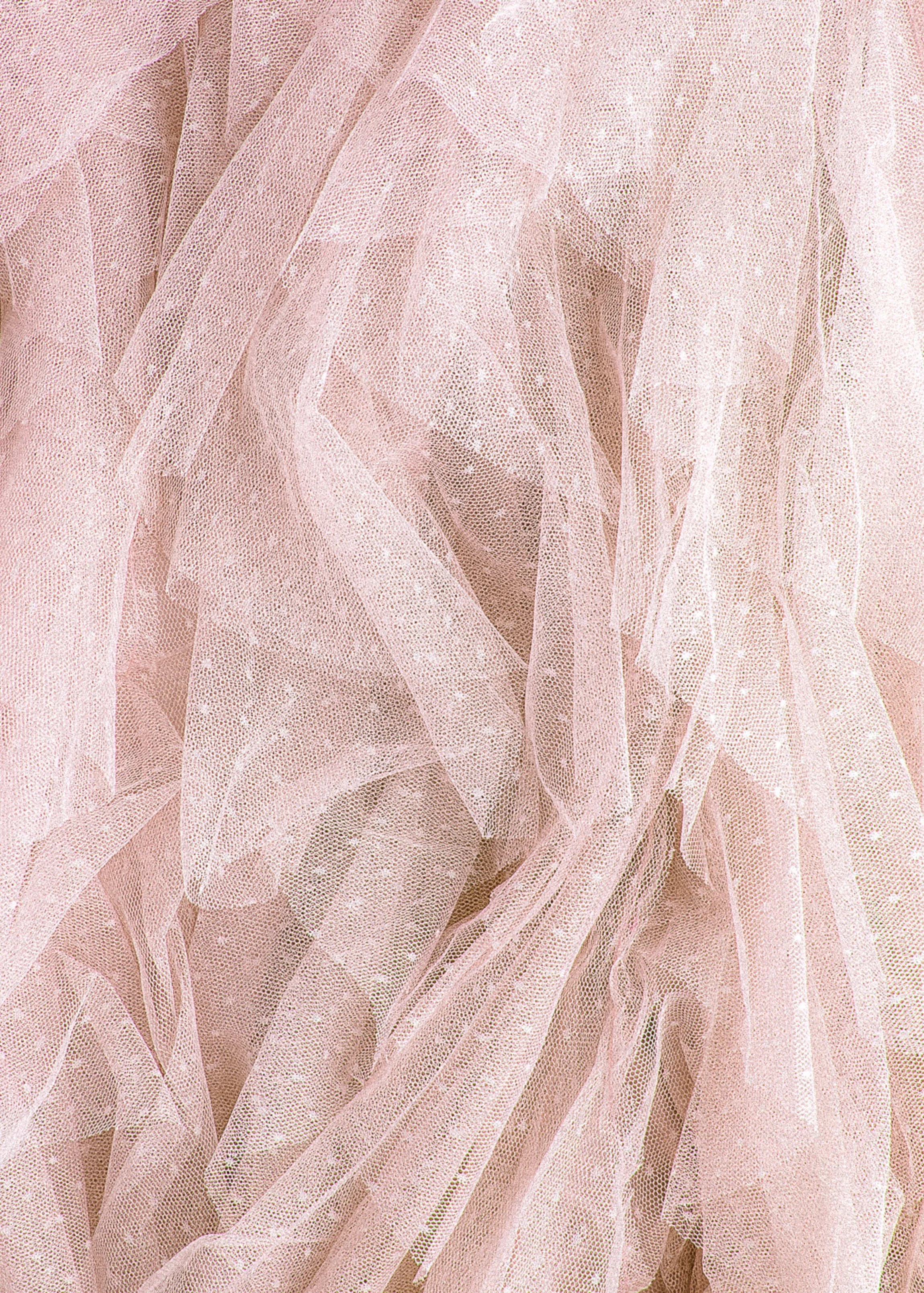 Soft, sheer pink tulle fabric with delicate white polka dots is layered and draped. The texture appears light and airy, conveying elegance.